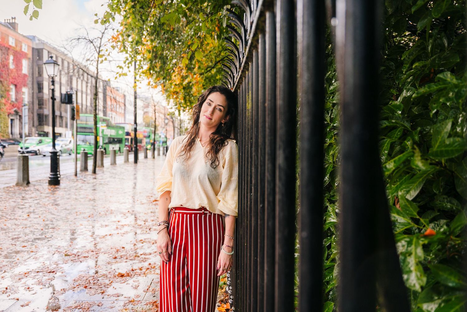 Autumn fashion shoot between black metal fence posts with greenery. professional headshots dublin photographer