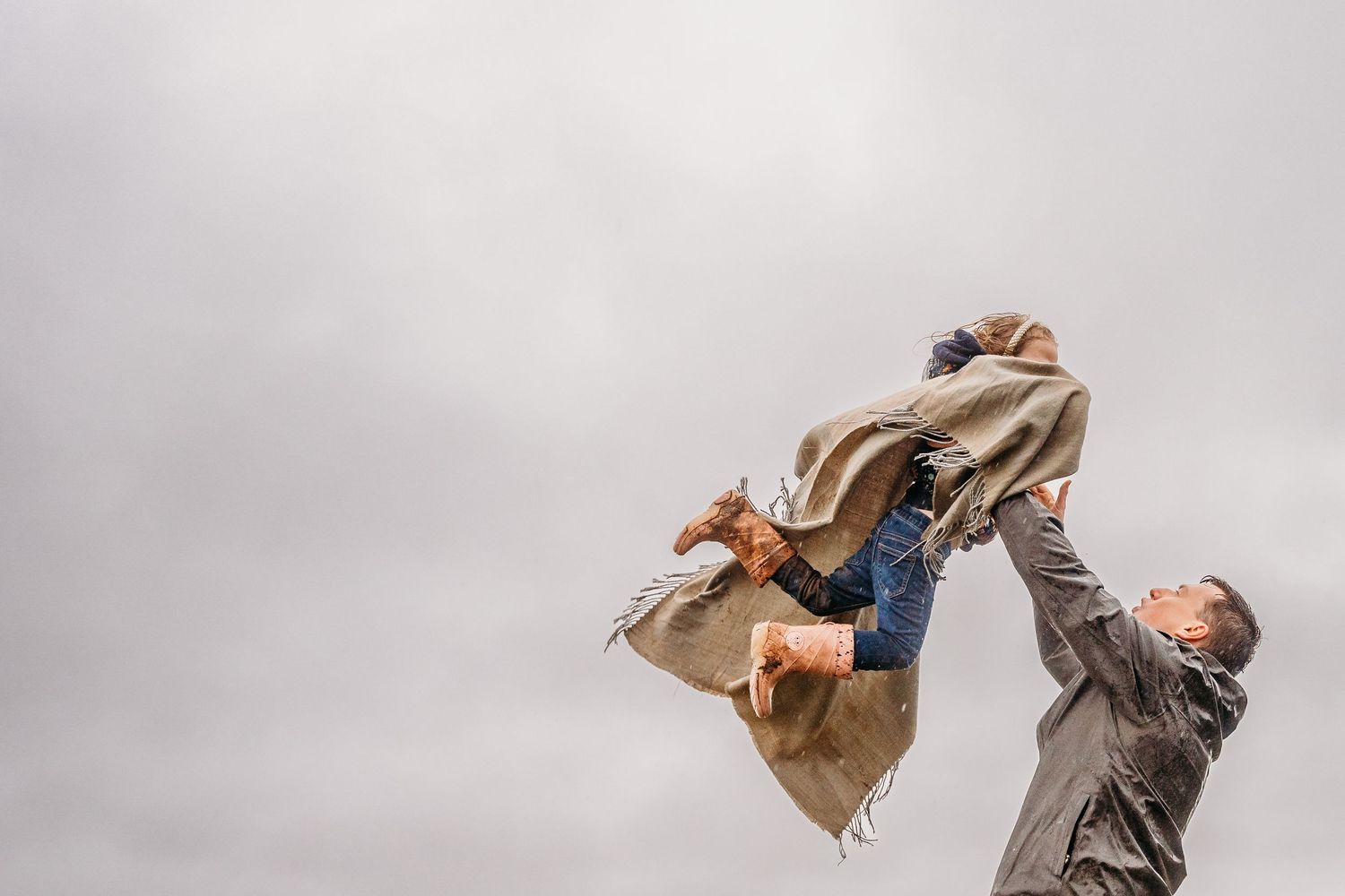 A candid moment of joyful movement as someone dances with a flowing brown jacket against a cloudy sky. family PHOTOGRAPHER Dublin