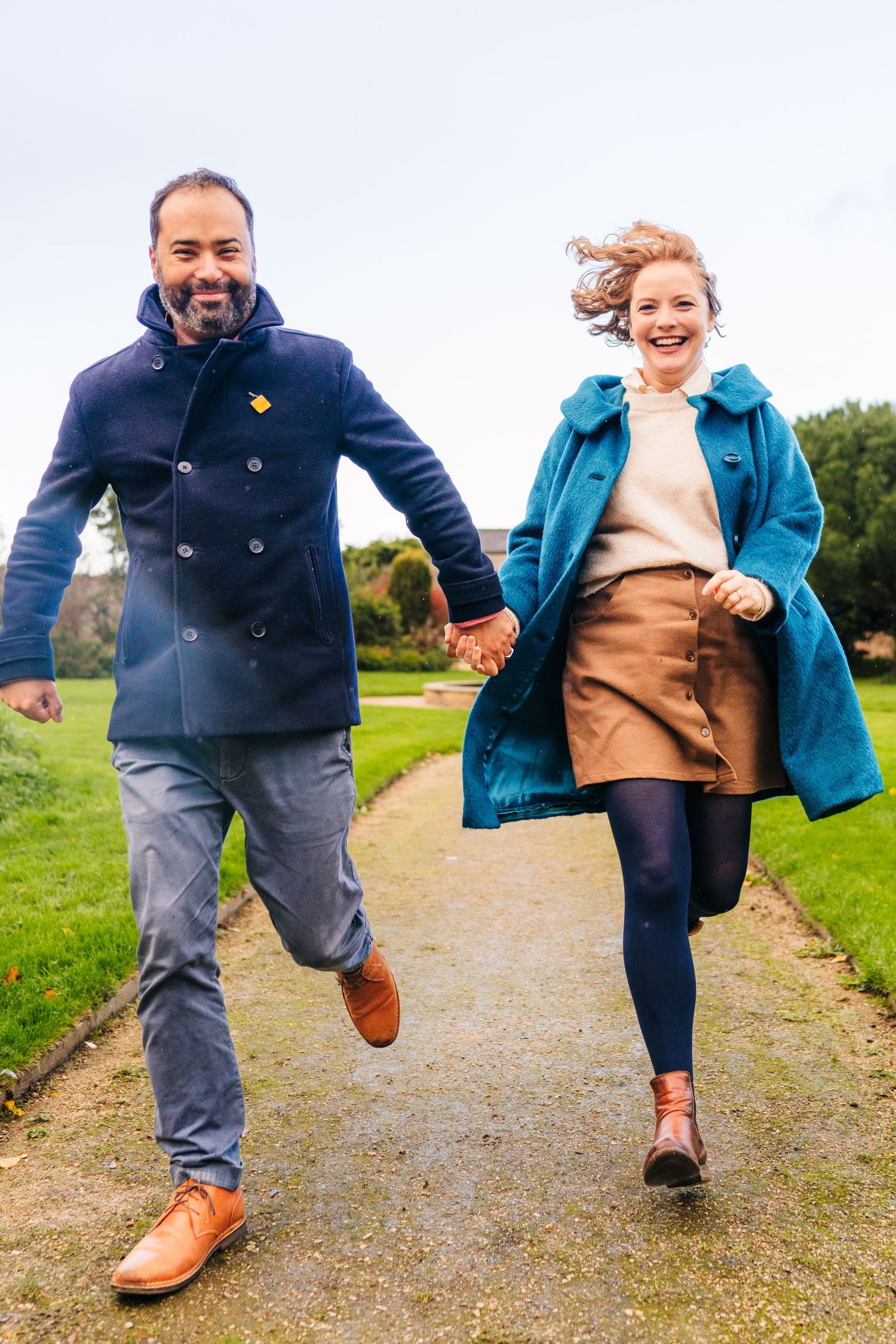 A playful sequence of people jumping and holding hands while walking on a gravel path in a green field. PHOTOGRAPHER Dublin ireland