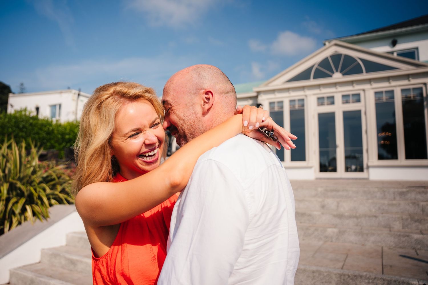 Couple in a coral dress and white shirt share tender romantic moments on an outdoor balcony during sunset. PHOTOGRAPHER Dublin ireland