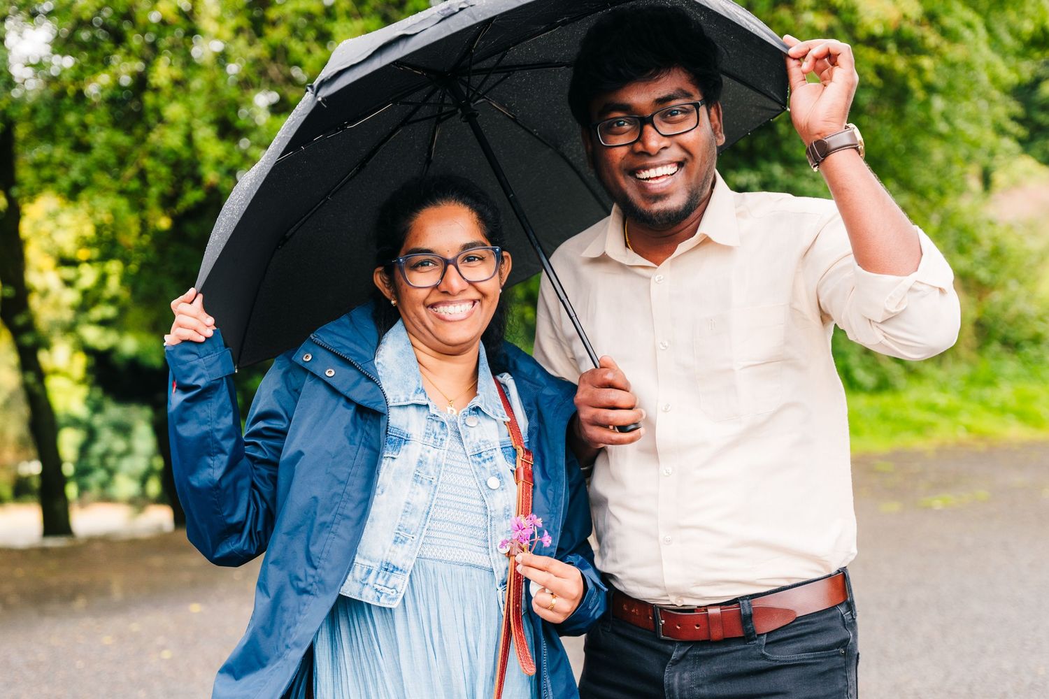 Couple laughing and walking together outdoors on a path surrounded by lush green trees. PHOTOGRAPHER Dublin ireland