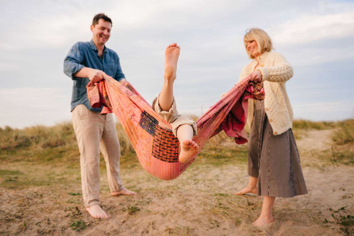 Couple in casual clothing sharing a romantic moment near the coastline on a cloudy day. family PHOTOGRAPHER Dublin