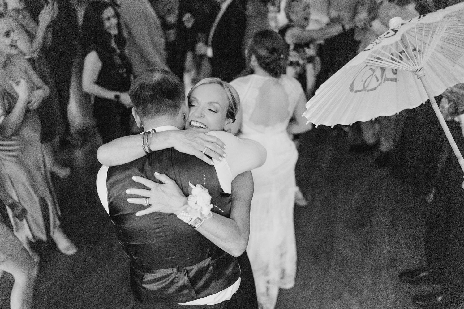 A black and white capture of wedding guests embracing on a lively dance floor. PHOTOGRAPHER Dublin Ireland Wedding