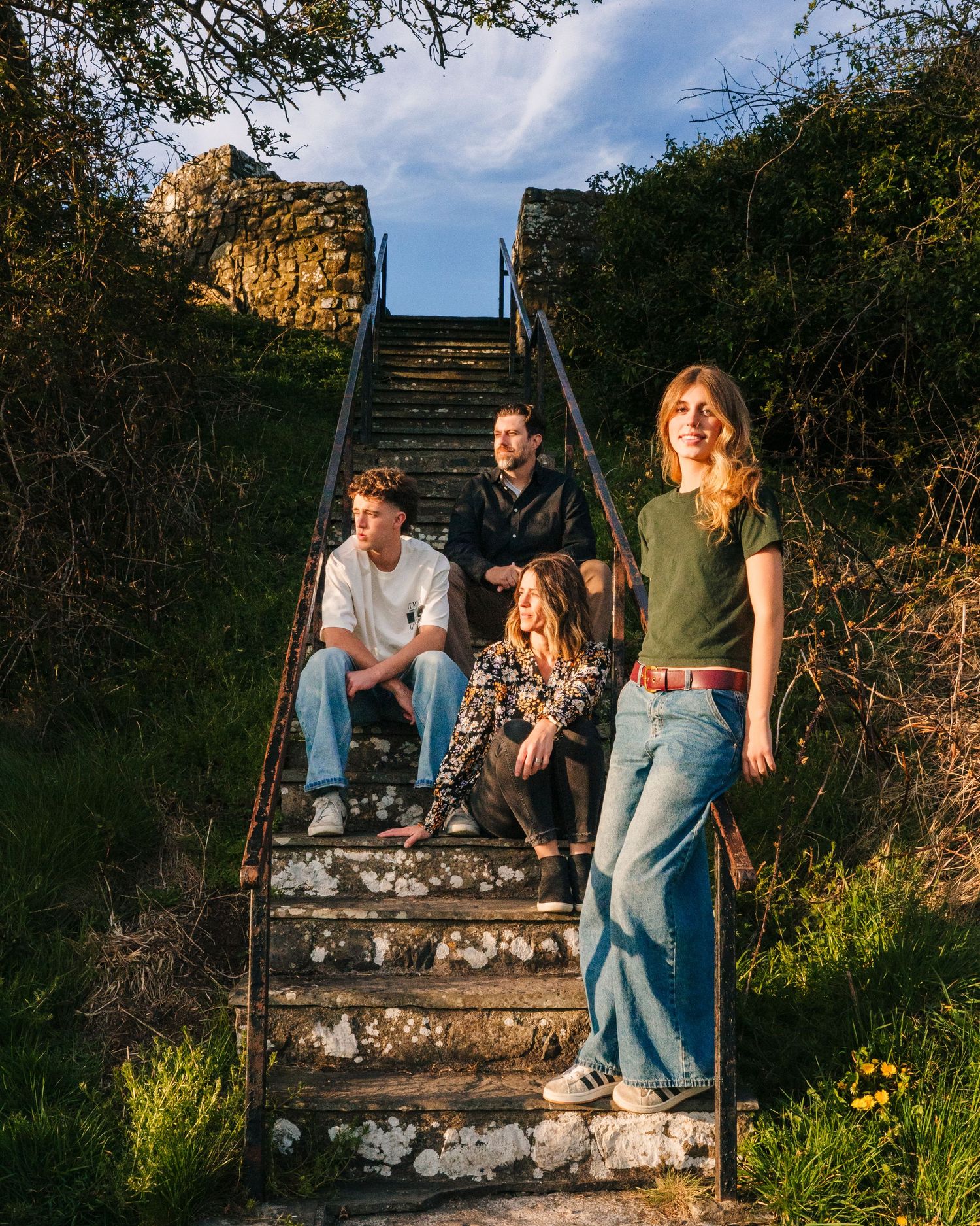 Group enjoying golden hour on stone steps in a garden setting illuminated by warm sunlight. Photographer Ireland dublin