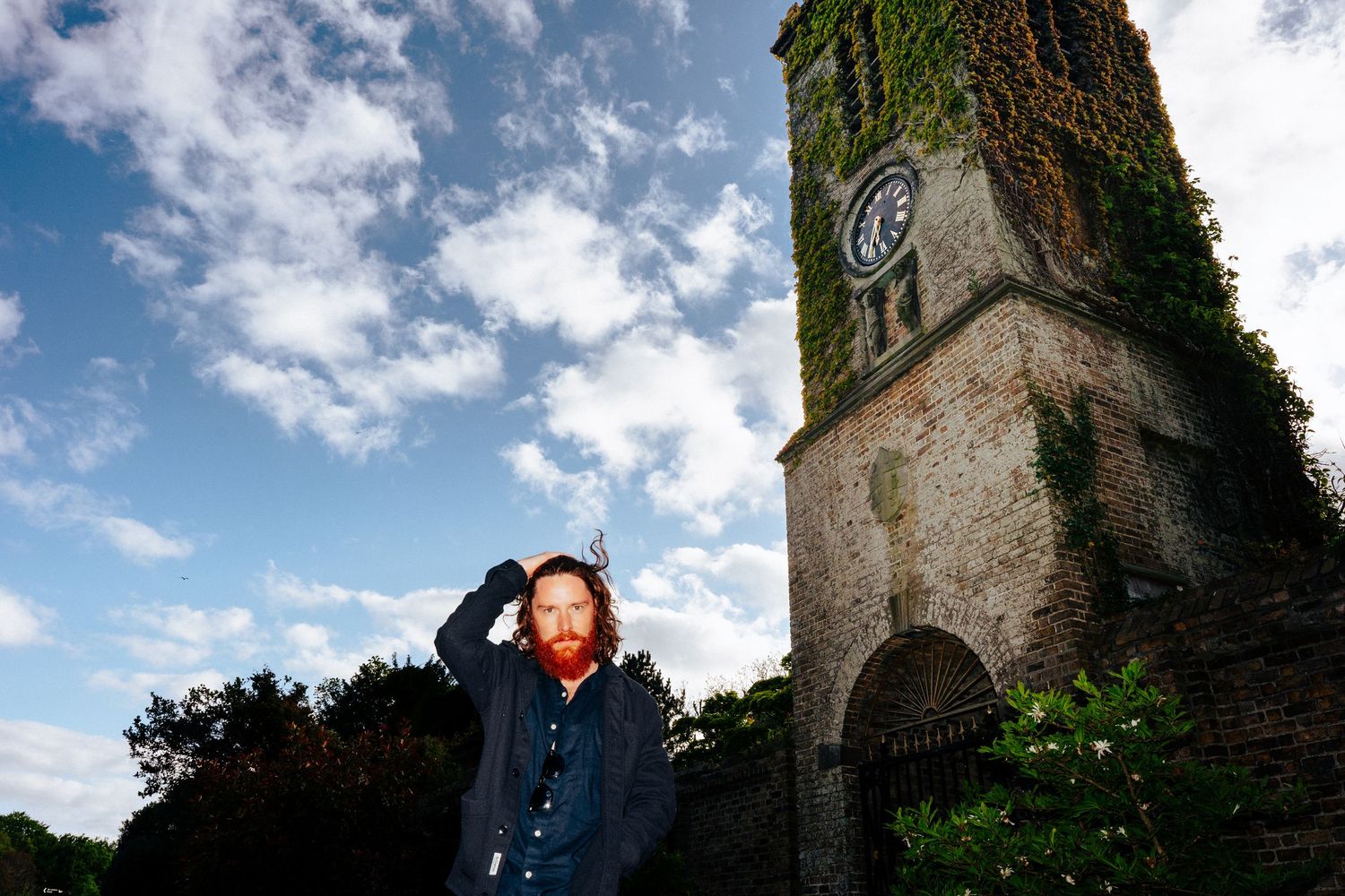 Old stone clock tower with ivy growing on walls against blue cloudy sky. PHOTOGRAPHER Dublin