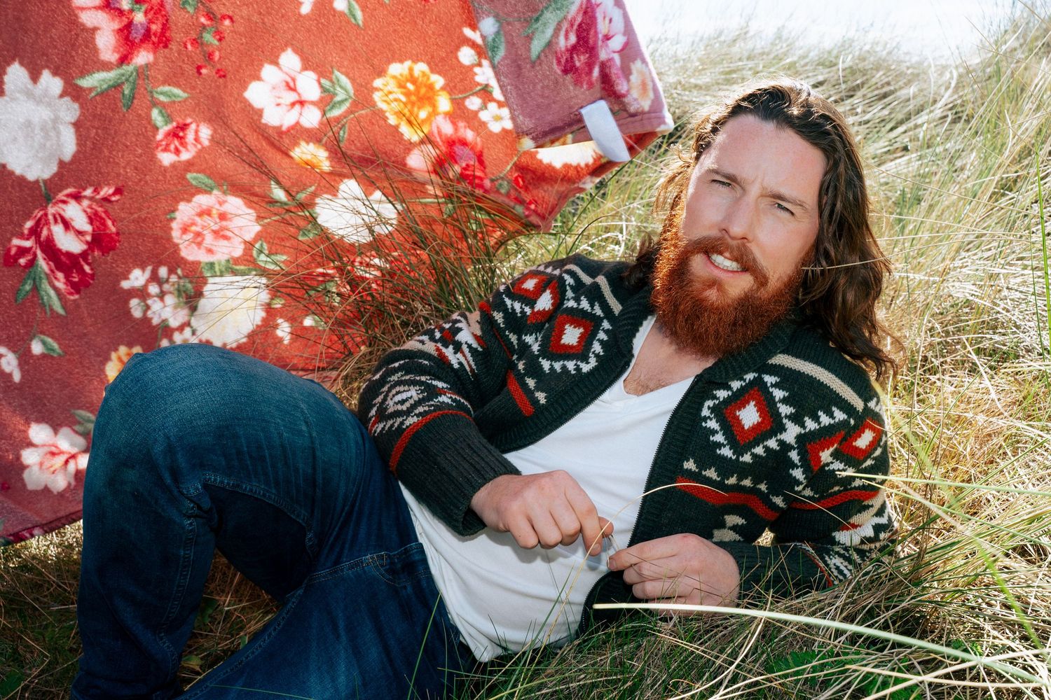 A musician performs against a vibrant red floral backdrop in a sunny outdoor setting. PHOTOGRAPHER Dublin