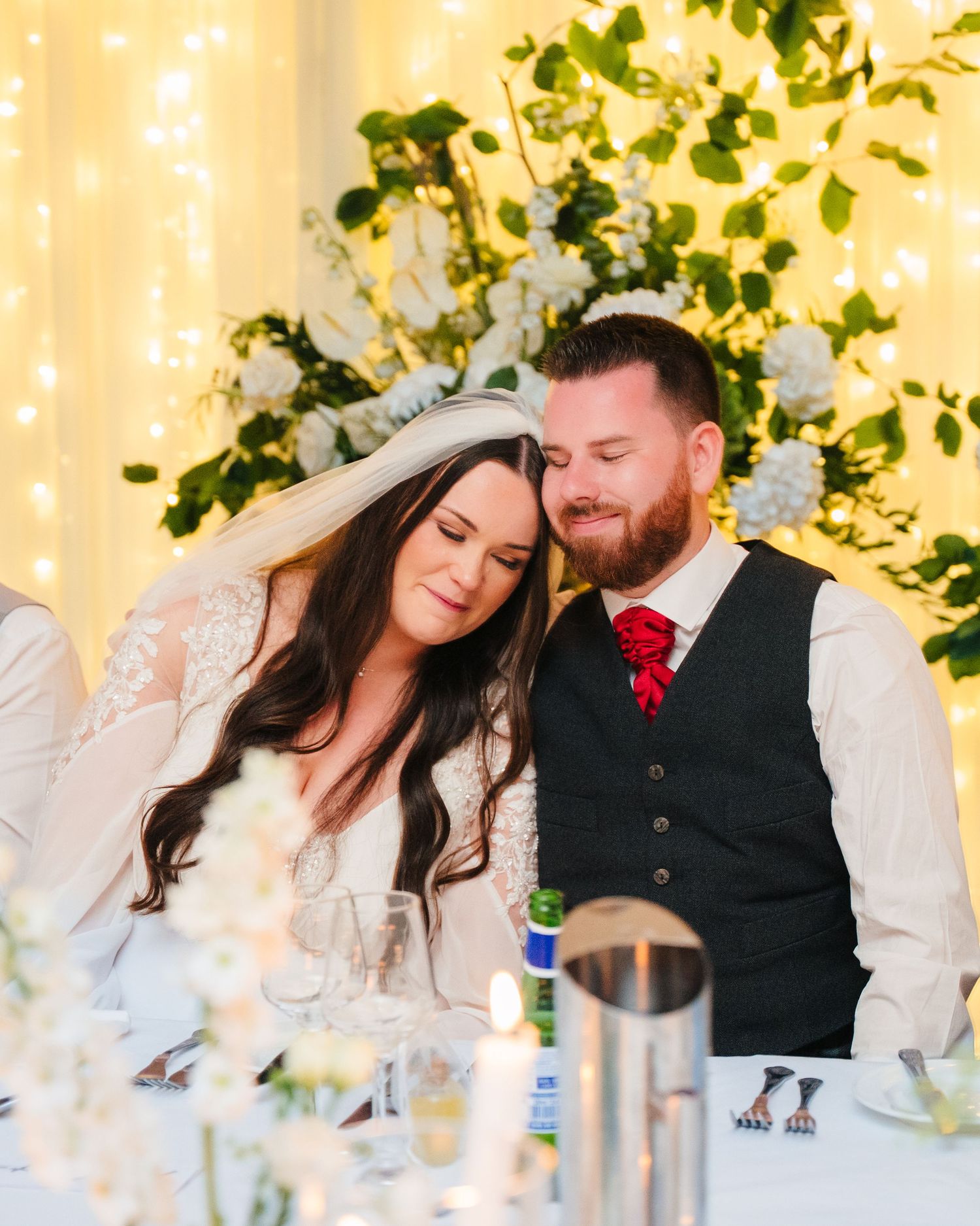 Intimate wedding reception scene with decorative lights and greenery in the background. Portmarnock Hotel Wedding PHOTOGRAPHER Dublin
