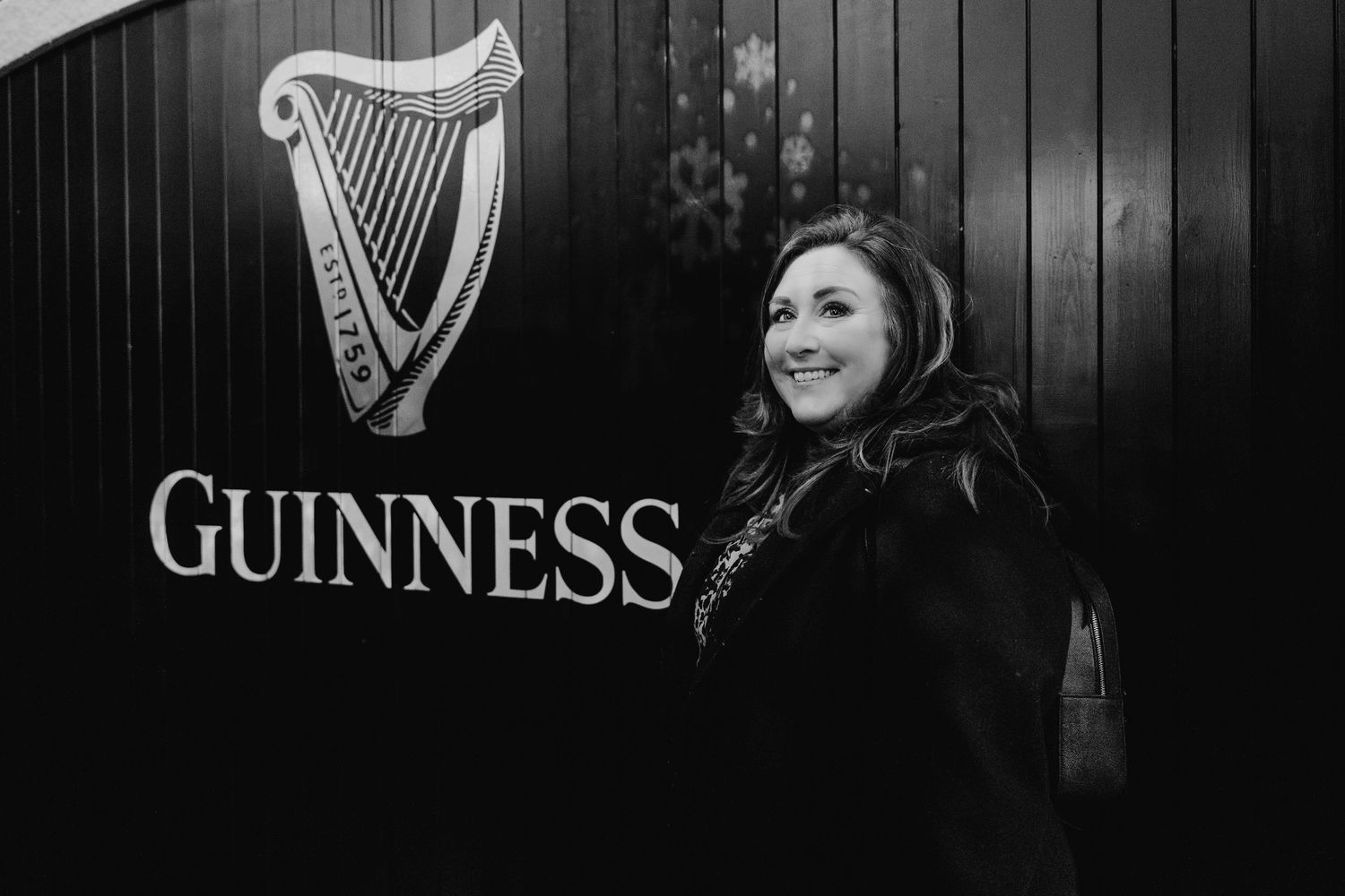 Black and white photo featuring Guinness logo and harp symbols on wooden wall. family PHOTOGRAPHER Dublin