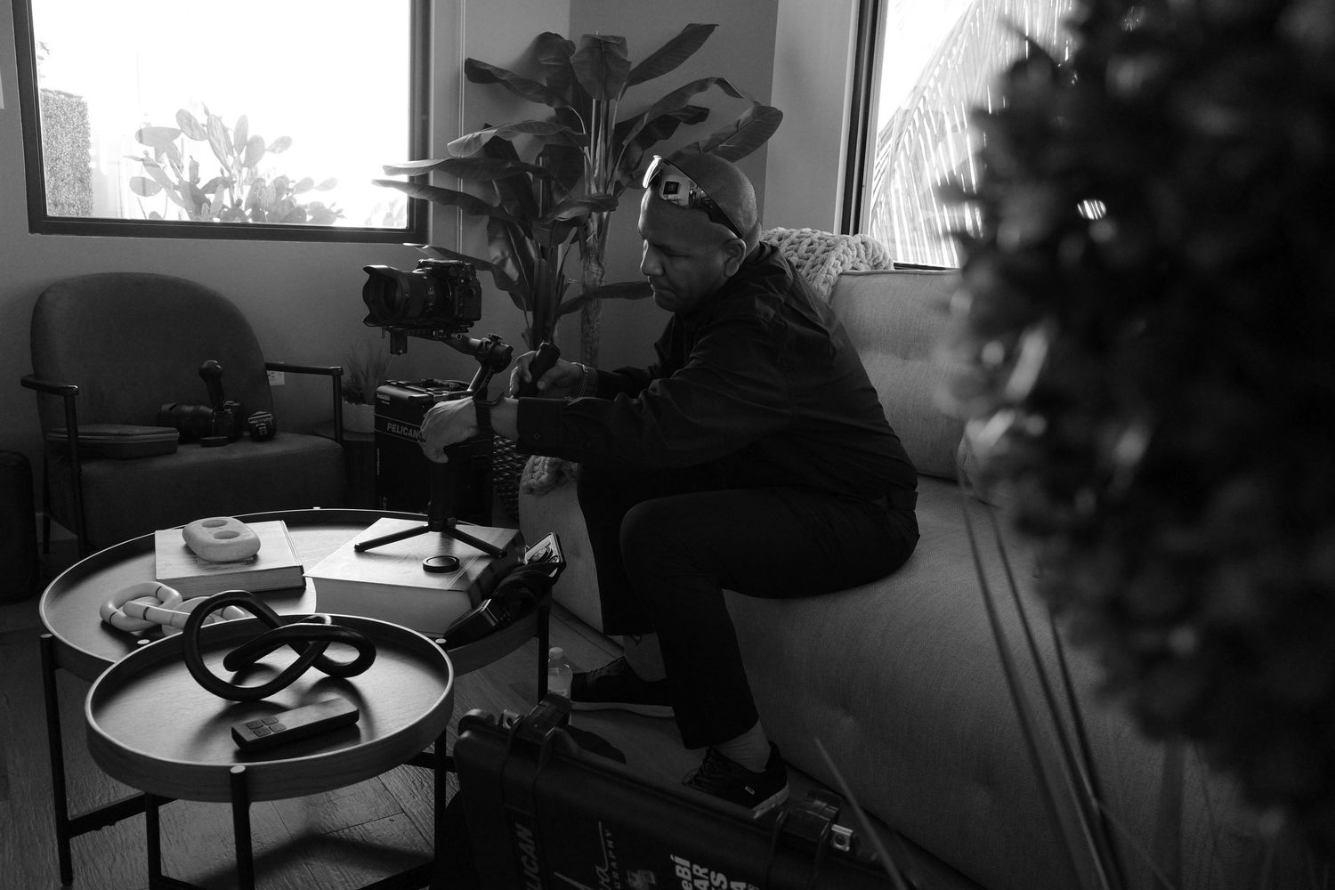 Black and white photo of a videographer operating a camera on a gimbal in an indoor studio setting.