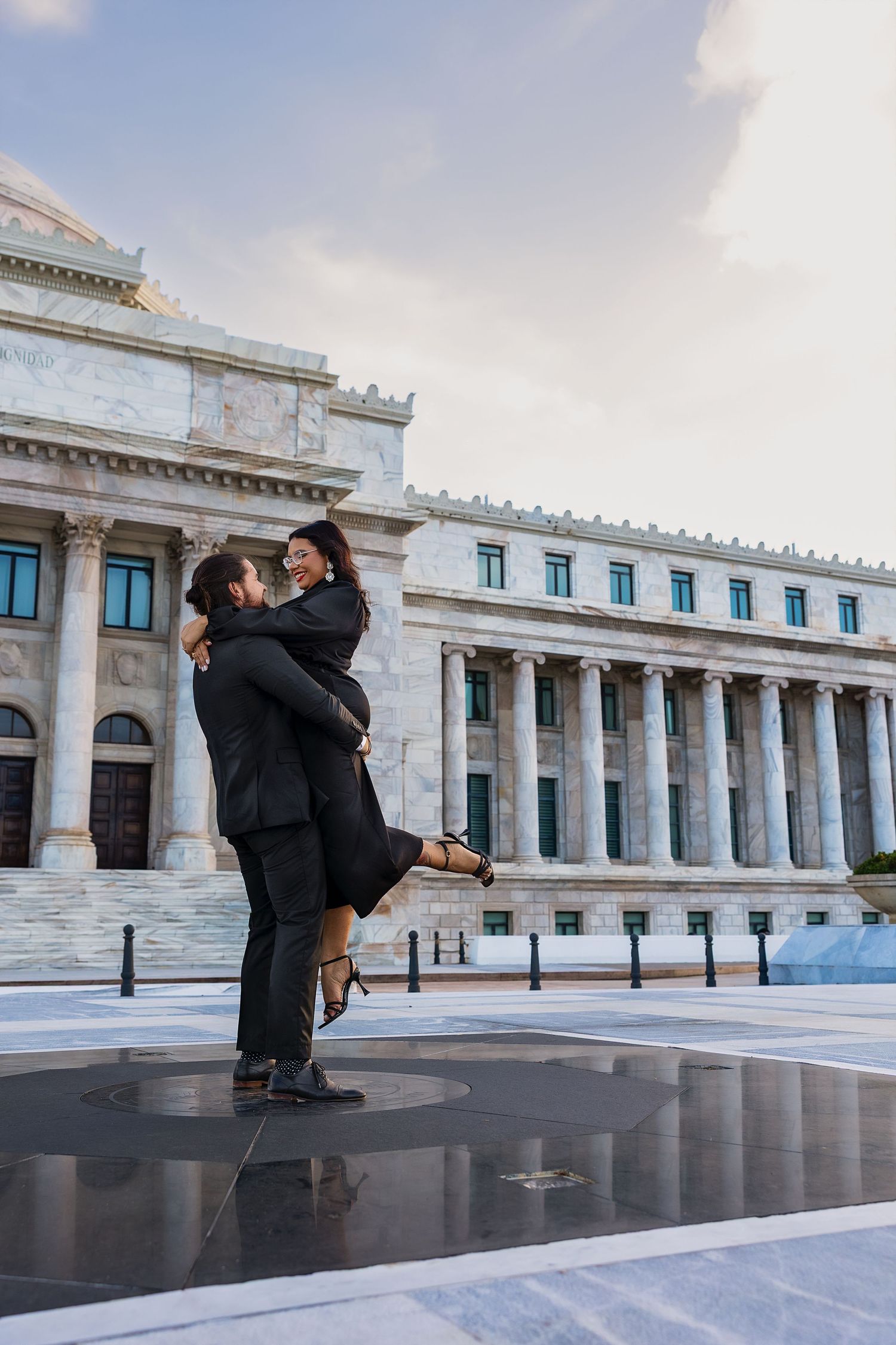 A romantic proposal scene unfolds in front of a grand neoclassical building with white columns and arches.