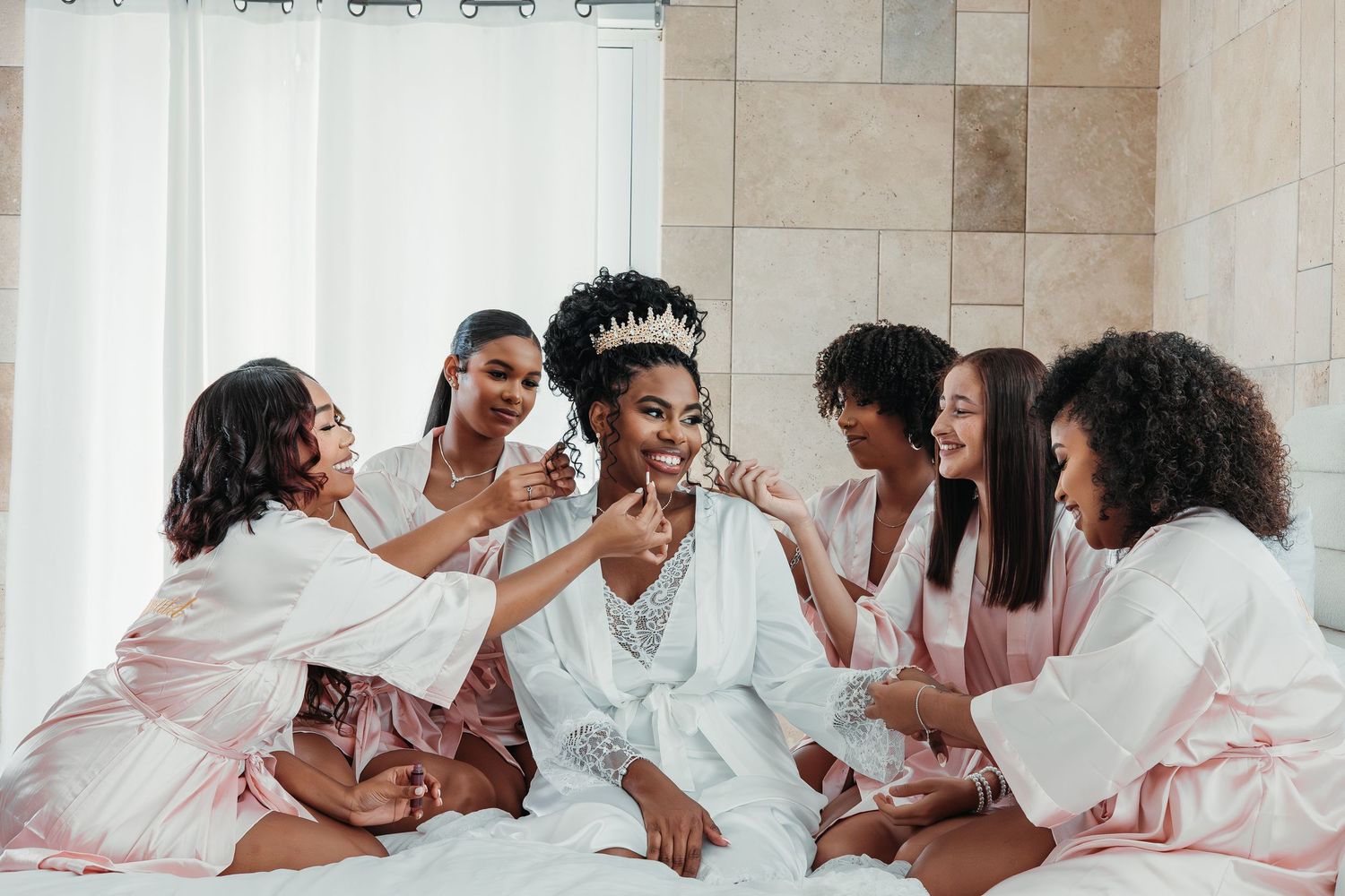 A group of friends in pink and white robes laugh and celebrate together during a joyful gathering.