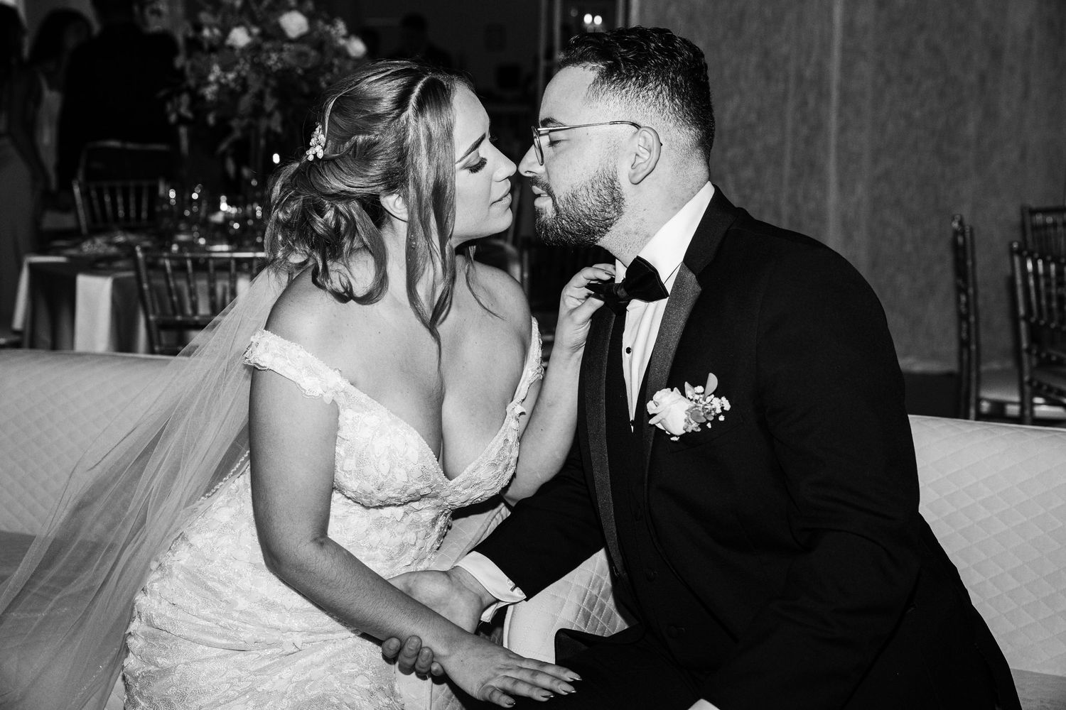 Black and white photo of a bride and groom sharing a romantic kiss at their elegant wedding reception.