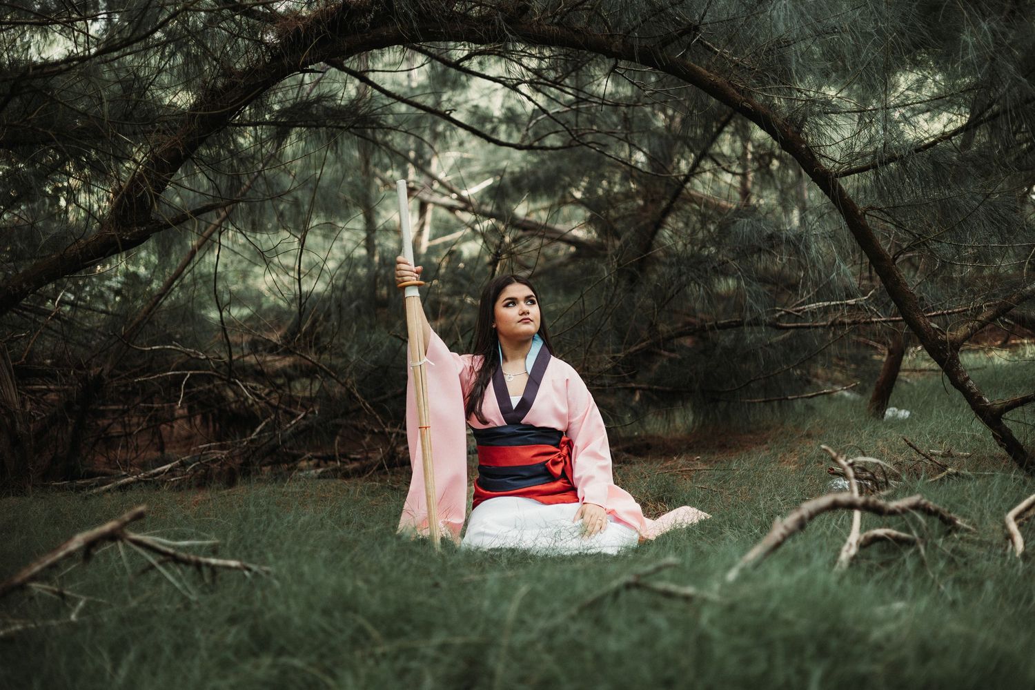 A person in traditional Japanese attire poses gracefully in a mystical forest setting.