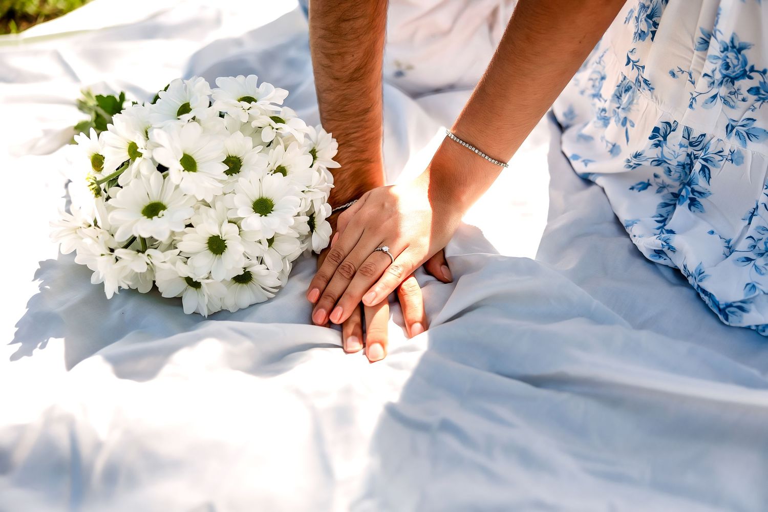A series of hands arranging white floral bouquets and centerpieces on a light blue tablecloth.