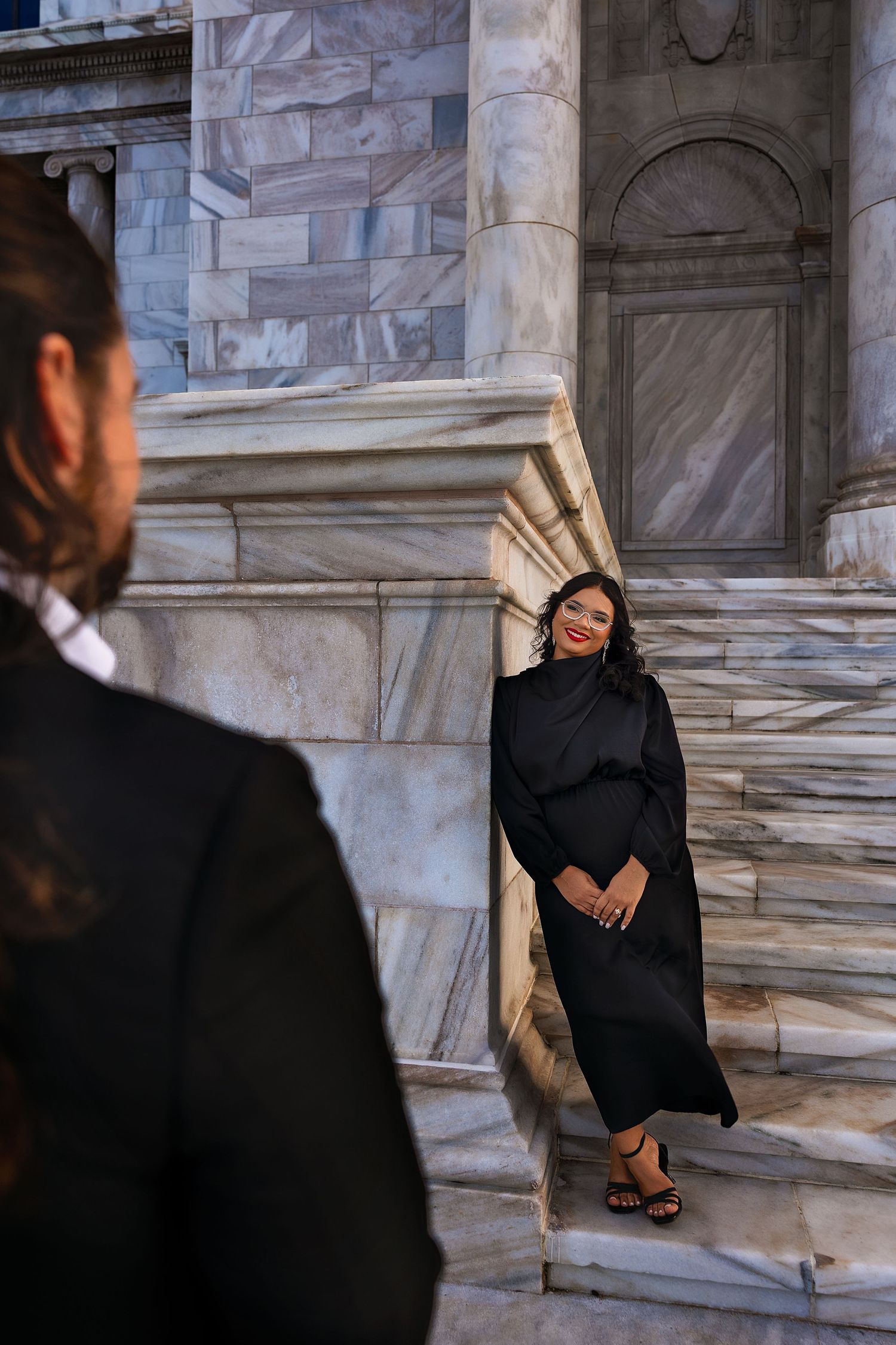 A sequence of photos showing someone in a black outfit sitting on marble steps while posing for a photoshoot.
