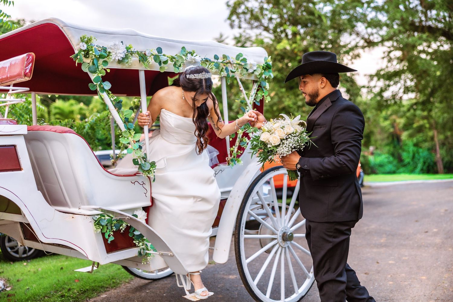A romantic carriage ride through a lush garden setting with white wedding decor and floral arrangements.