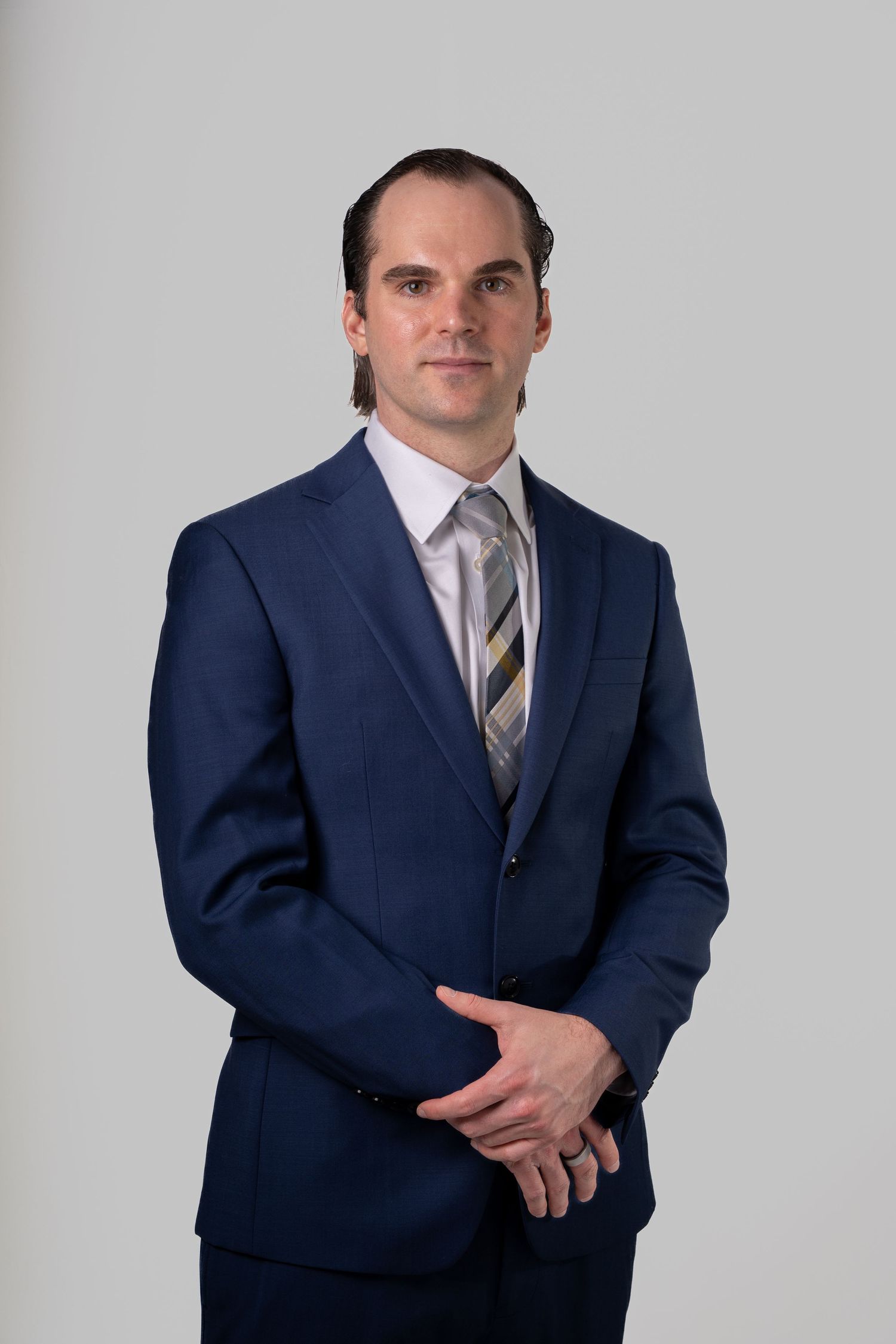 Professional wearing a navy blue suit and striped tie poses in various angles against a light gray background.