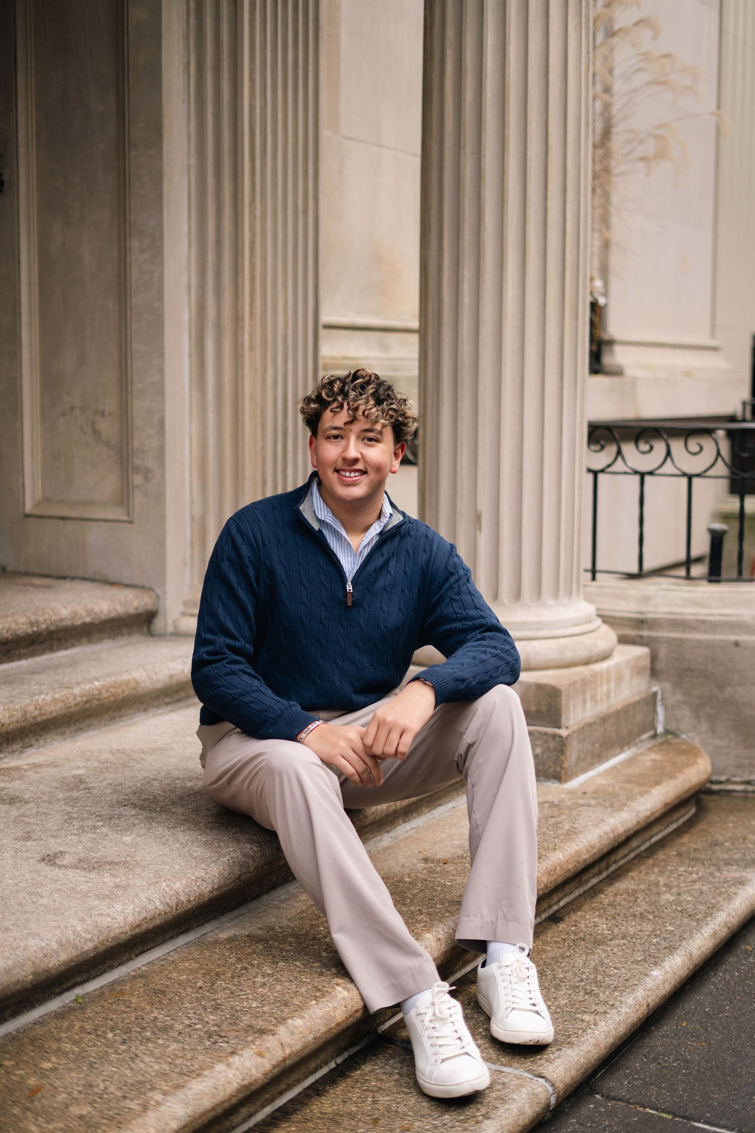A series of photos showing someone sitting on stone steps wearing a navy sweater, khaki pants, and white sneakers. central park east, ues