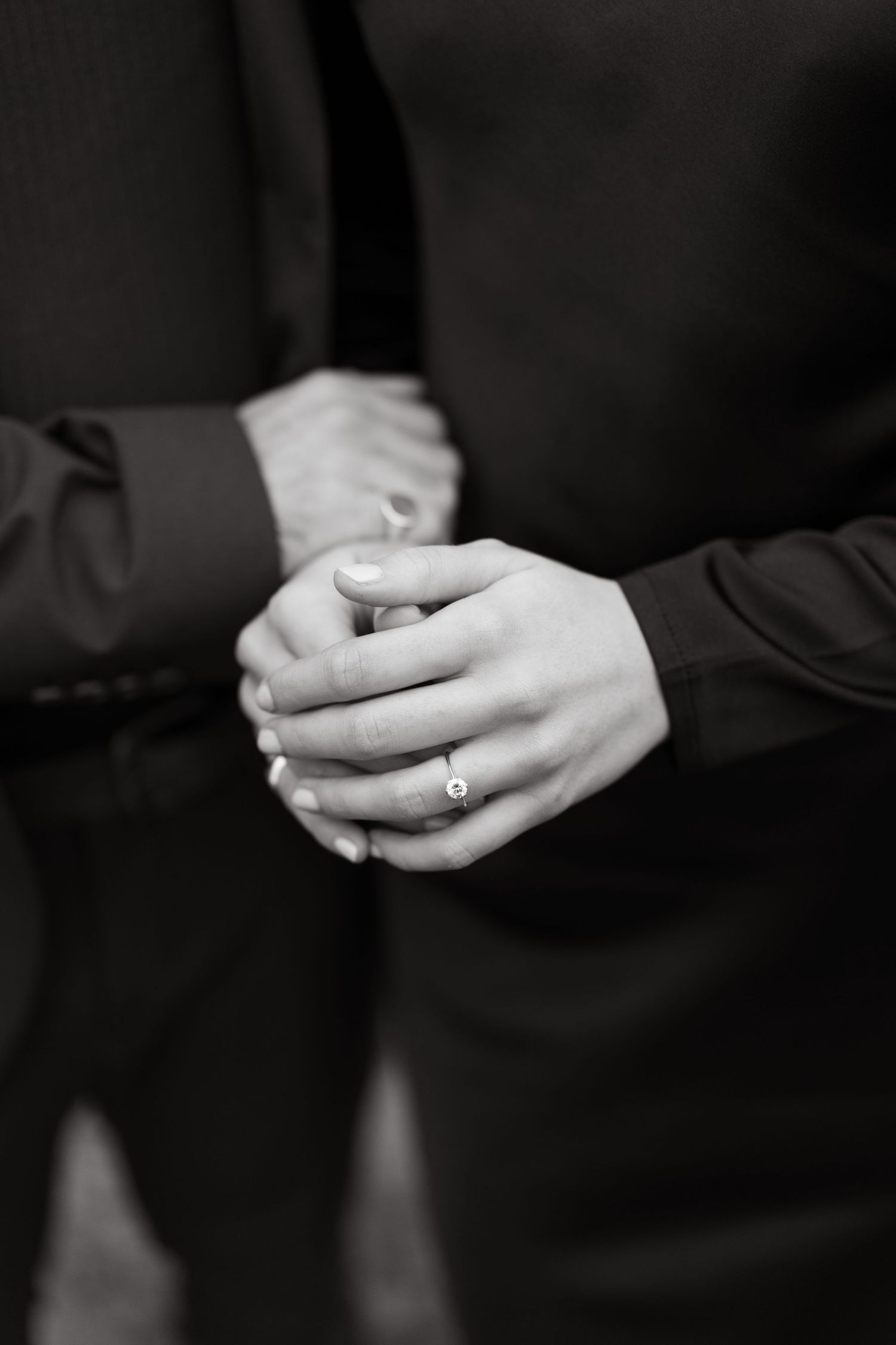 Elegant black and white photo of clasped hands with an engagement ring.