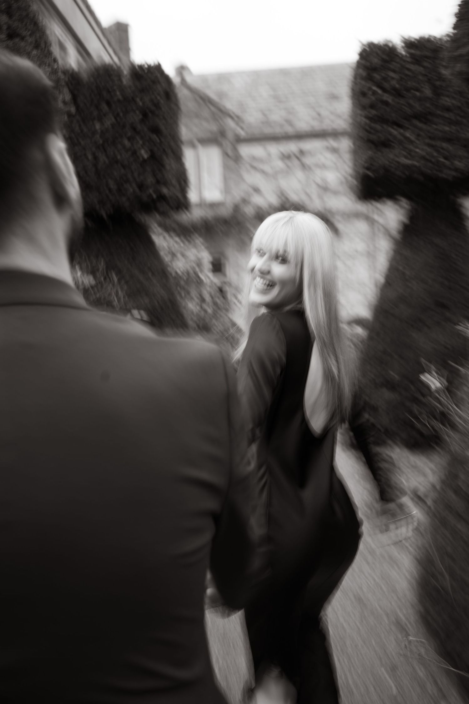 Artistic black and white motion blur photograph capturing two people in an outdoor garden setting.