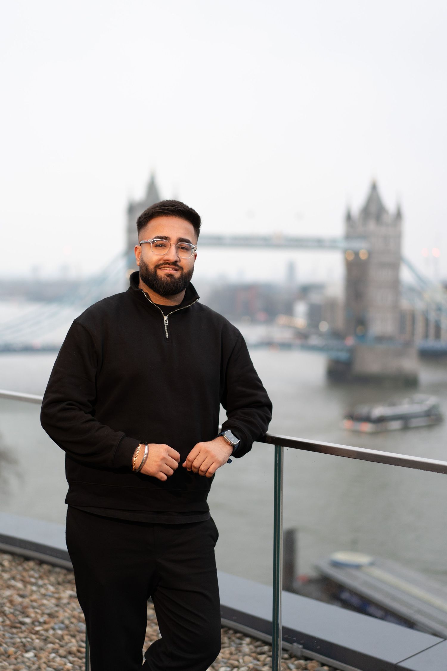 Tourist enjoying scenic view of London's Tower Bridge from elevated viewpoint along the Thames River.