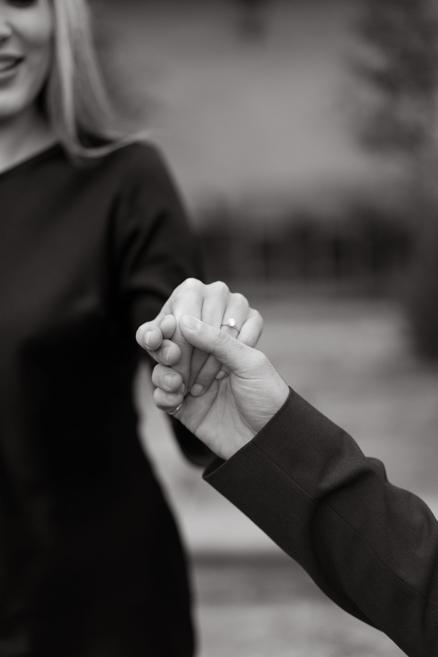 Close-up black and white photo of two hands clasped together in an intimate gesture.
