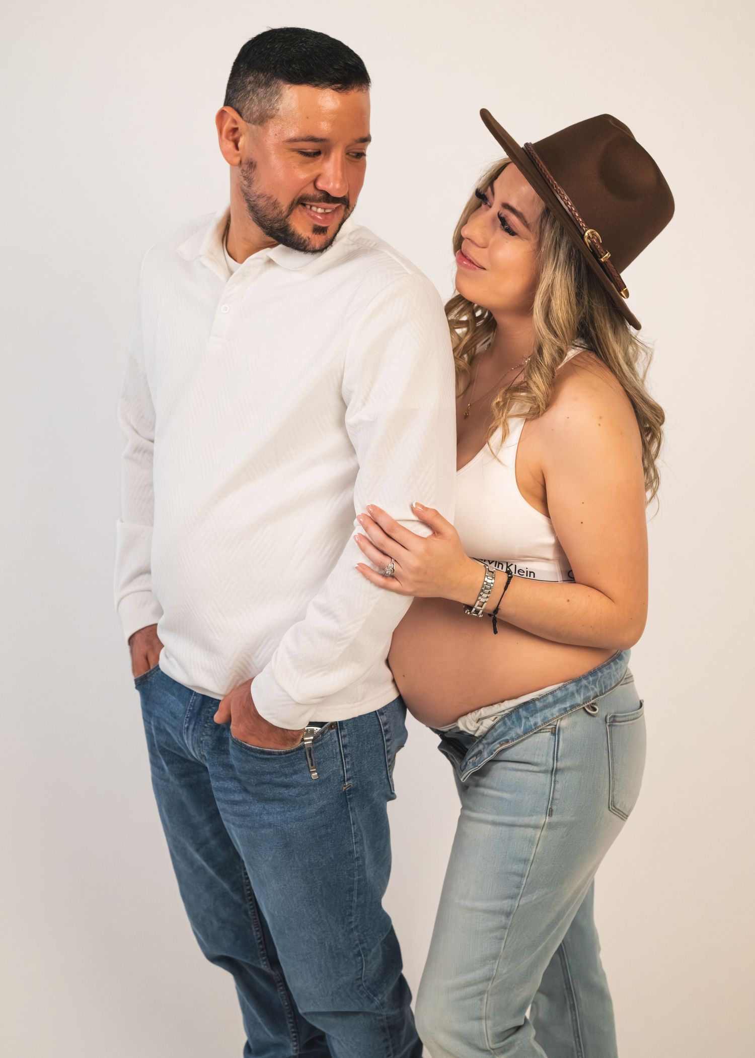 A couple in casual attire shares intimate moments in a series of playful poses against a white background.