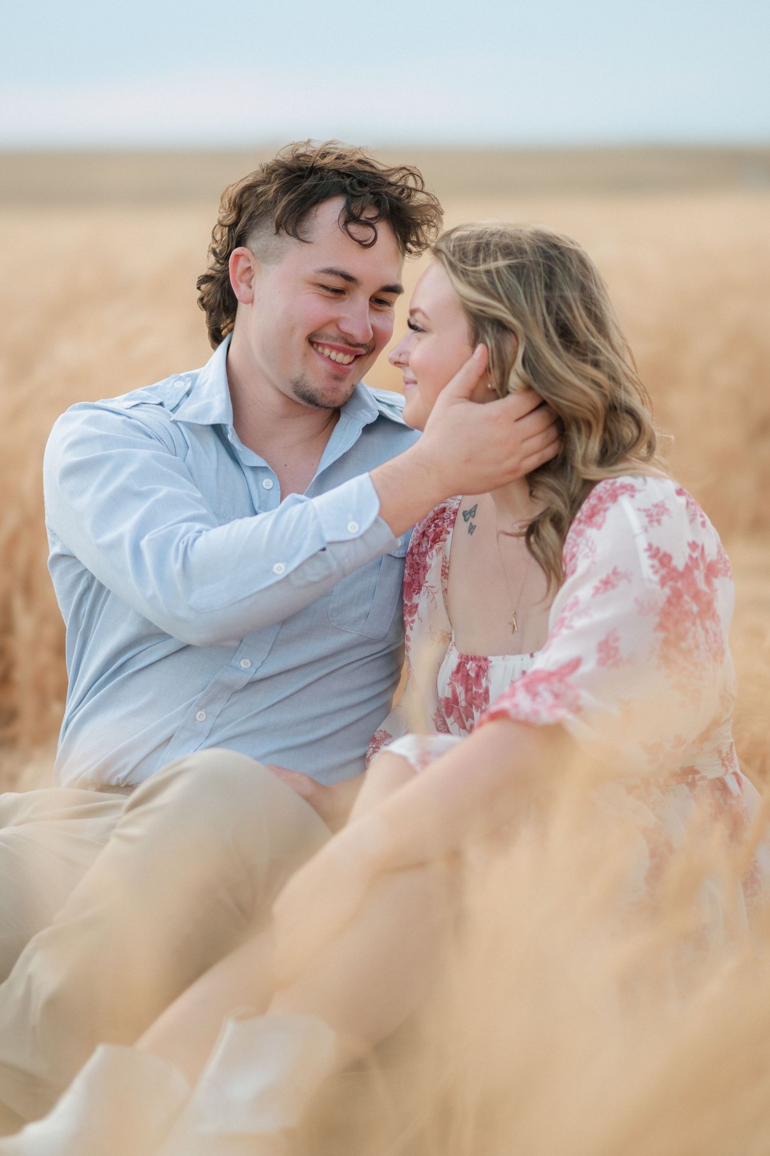 Romantic couple sharing intimate moments in a wheat field during golden hour.