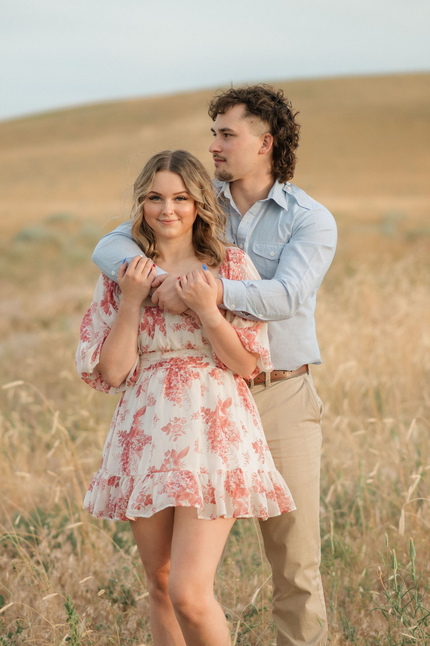 A couple shares intimate moments in a golden field during sunset, creating a romantic outdoor photoshoot.