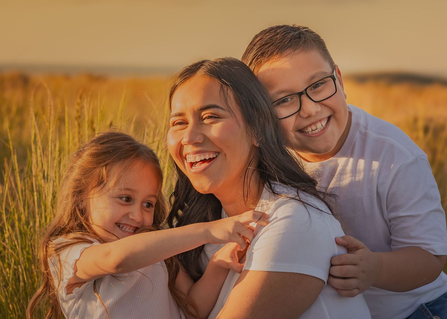 Candid family photography session in golden sunlit field at sunset.
