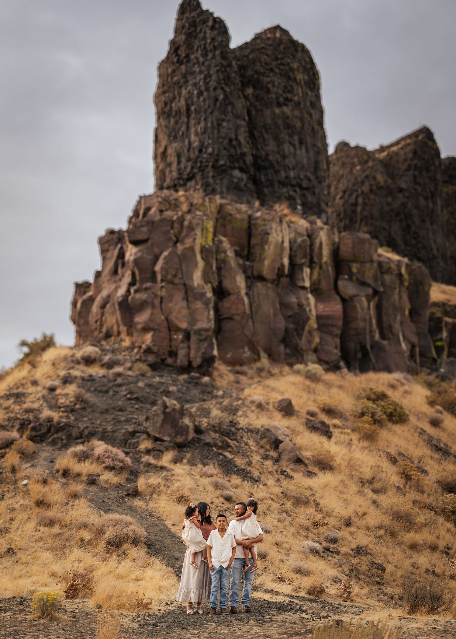 Panoramic sequence of rugged basalt cliffs and rocky terrain leading to people standing on a hiking trail.