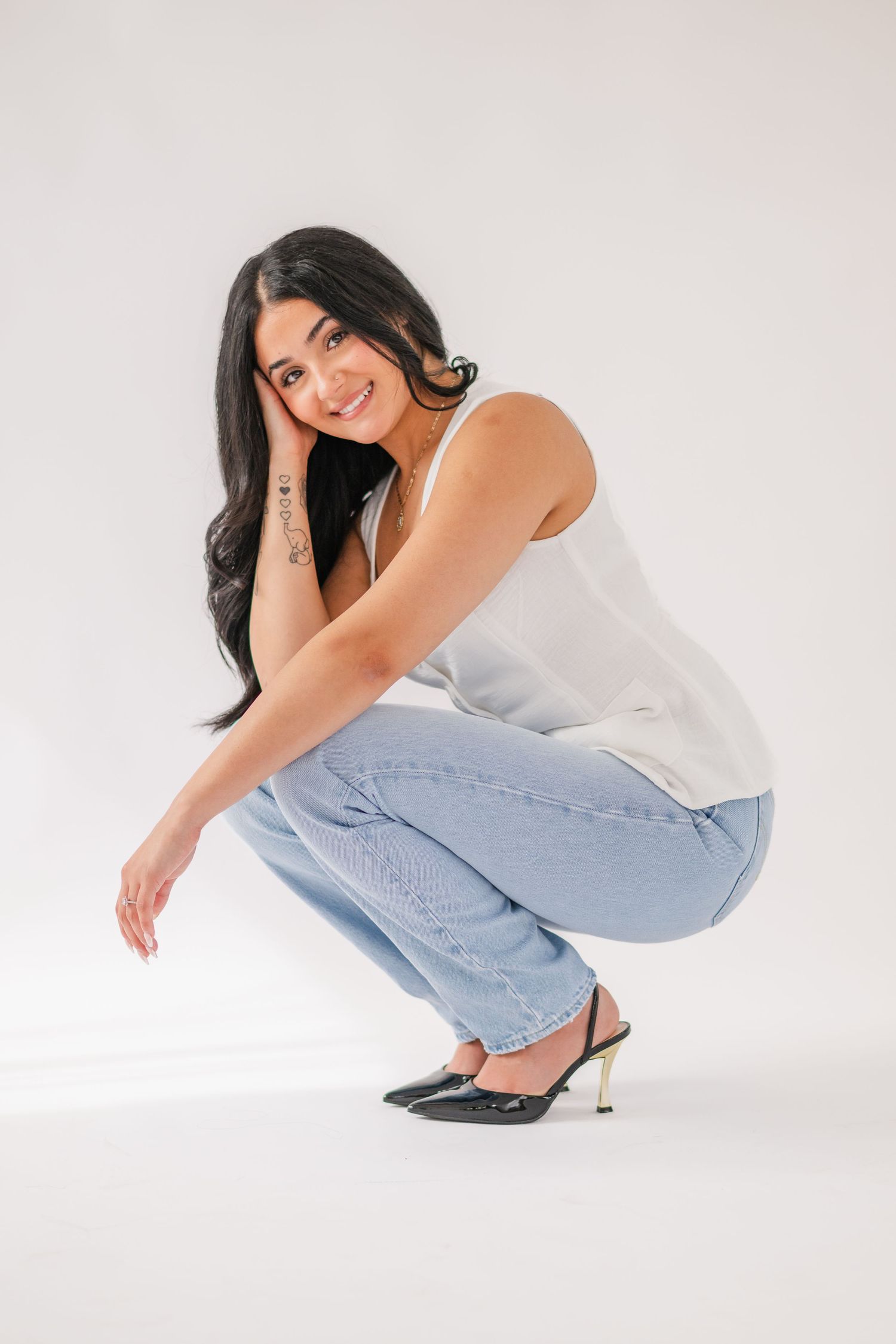 Person in white tank top and light blue jeans poses in sequence against white background showing different crouching positions.