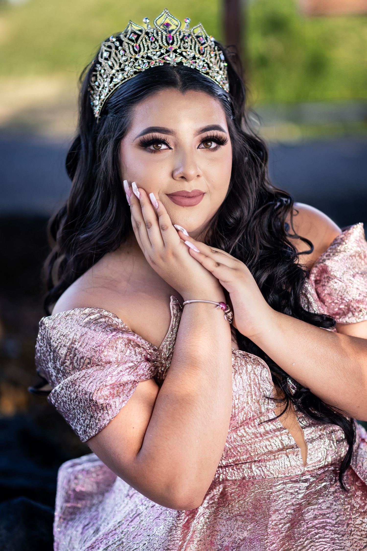 A person in a pink sequined gown and tiara poses outdoors for a series of glamorous portrait photos.