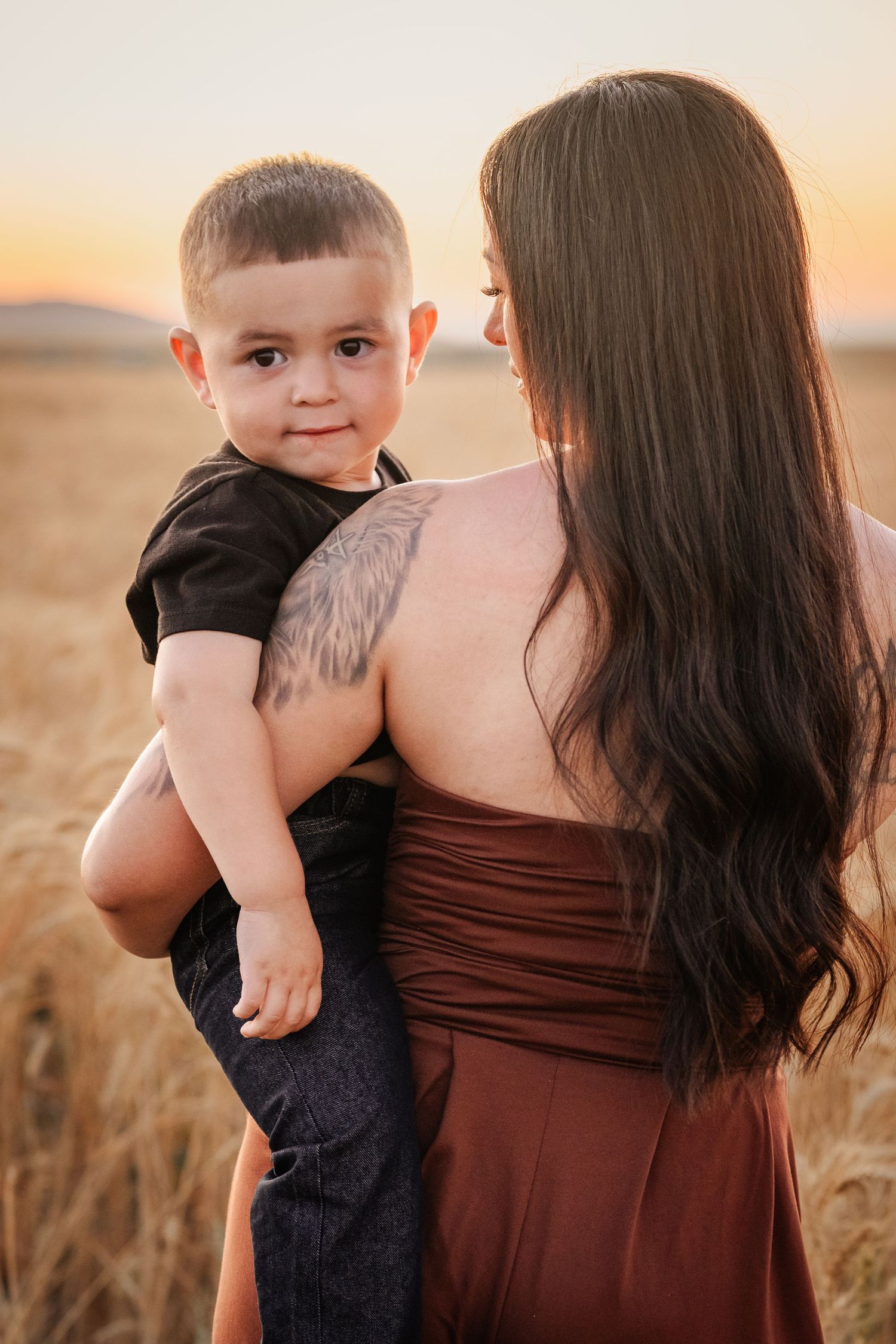 A tender moment captured between parent and child in a golden wheat field at sunset.