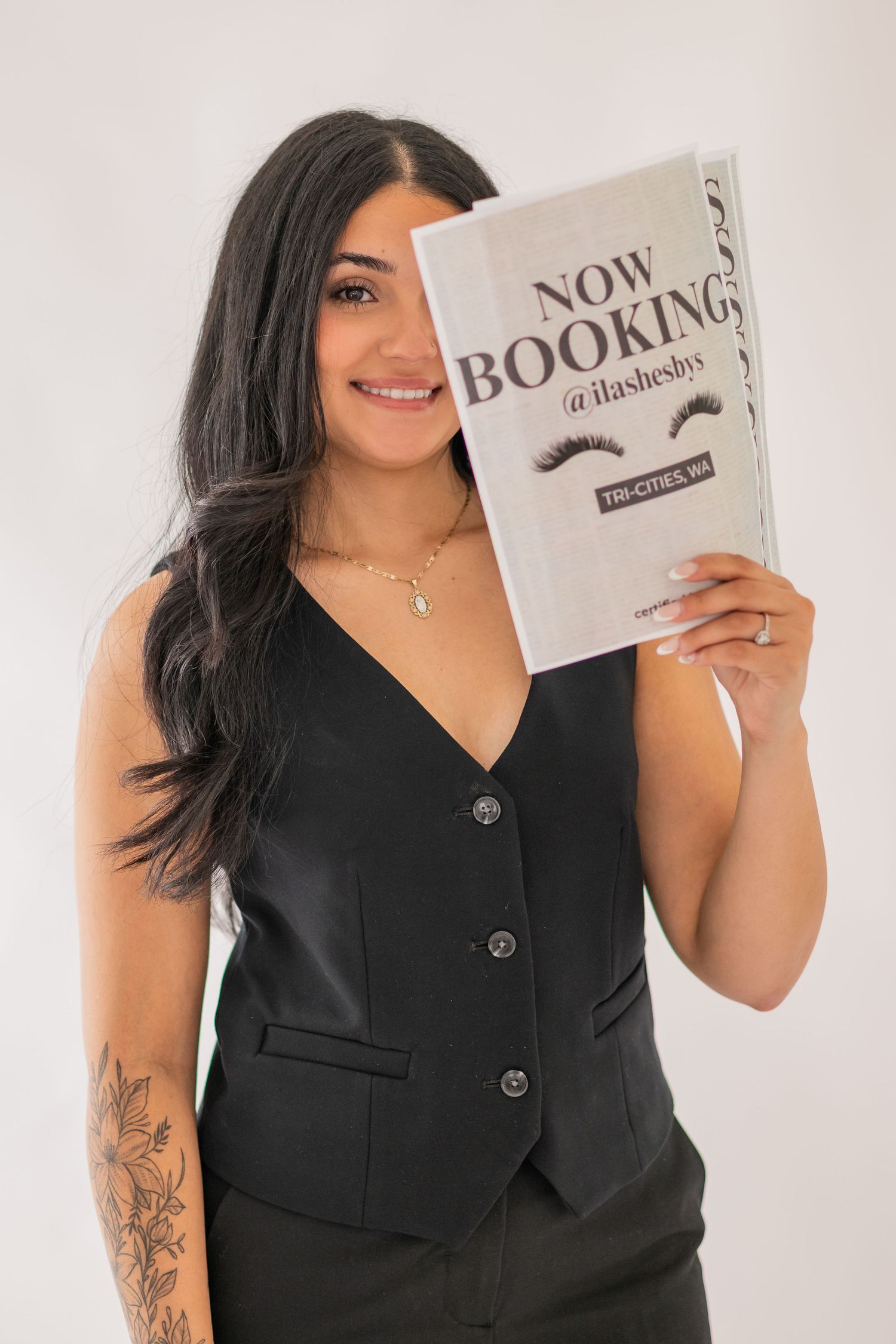 A person in a black sleeveless top poses with a book against a white background in a series of photos.
