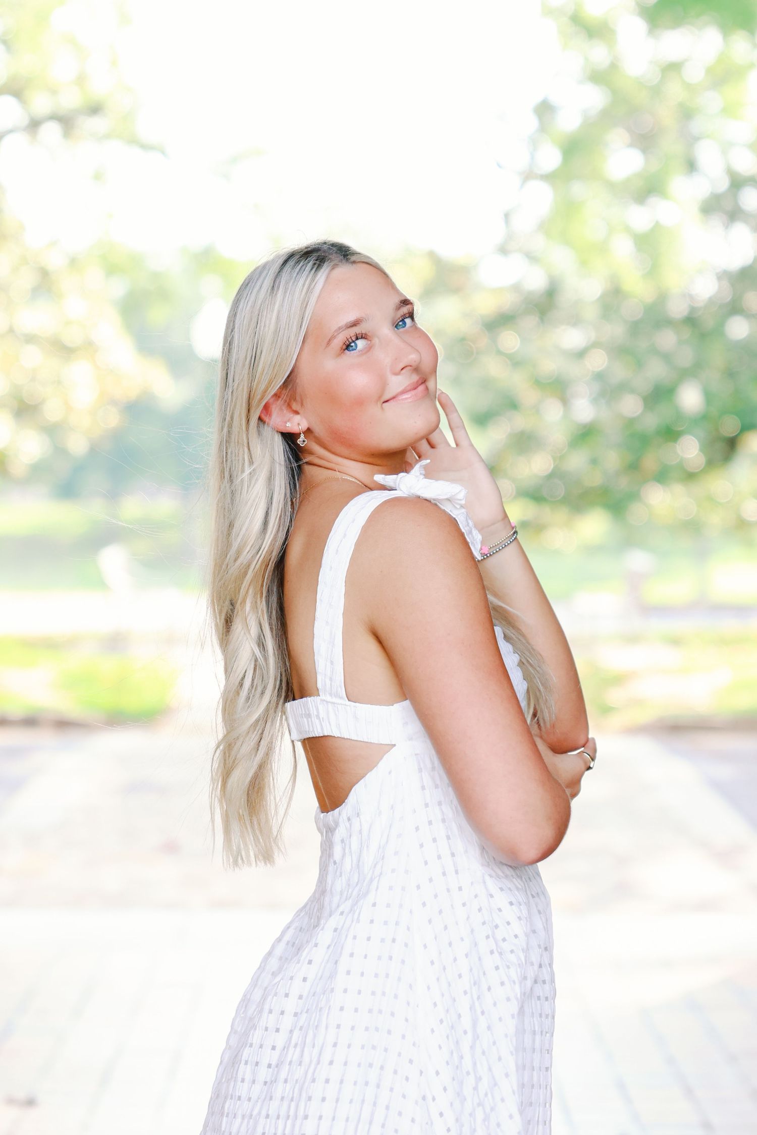 Person in white summer dress poses against blurred outdoor background in series of artistic portrait shots.