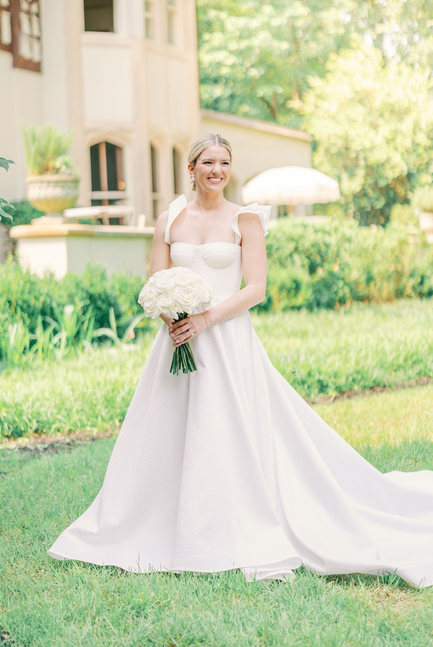 Classic white wedding dress with sweetheart neckline and flowing train captured in front of historic building.