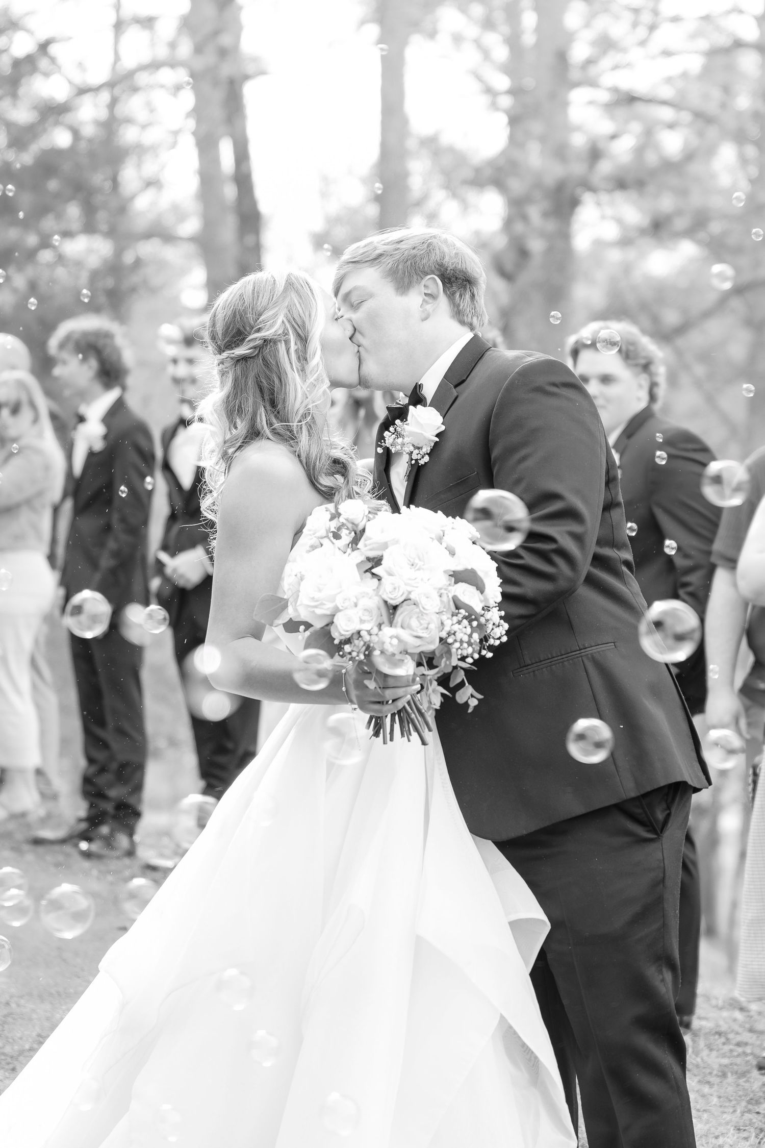 A celebratory moment surrounded by floating bubbles in an outdoor wedding setting.