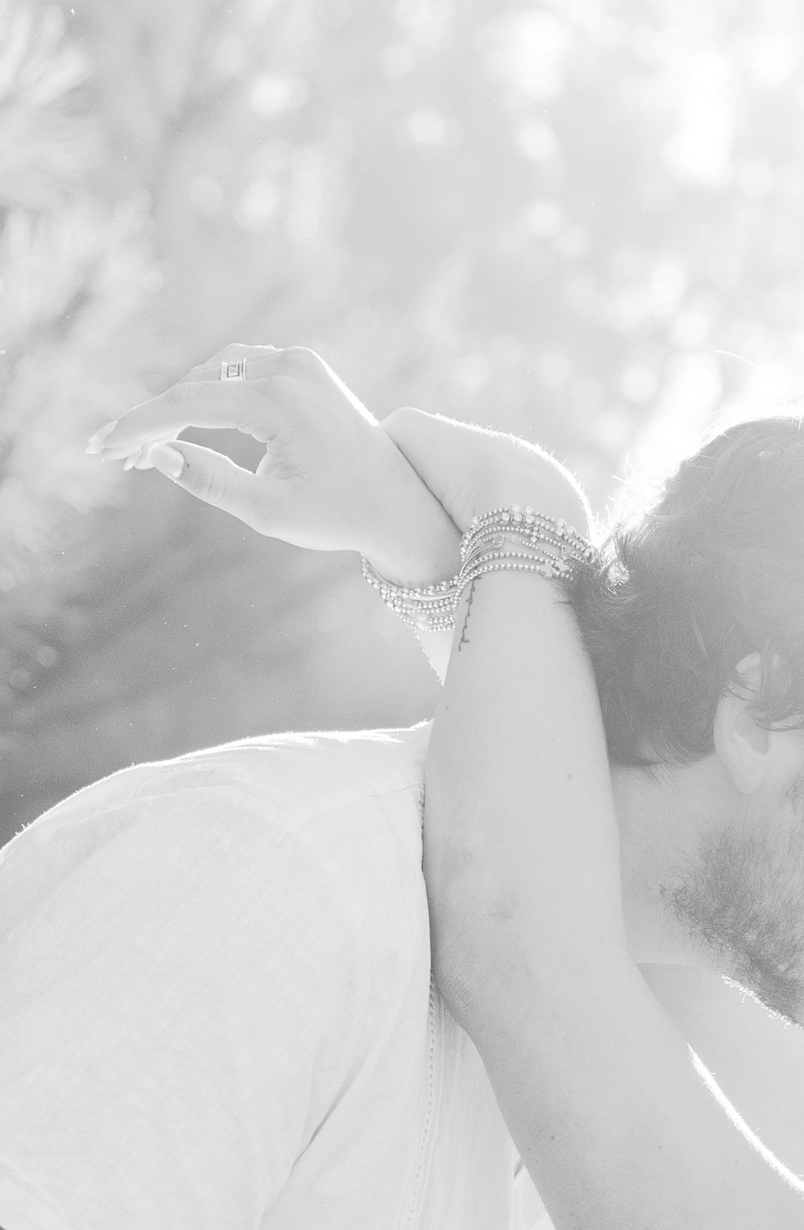 Close-up of hands with delicate bracelets against dreamy white background.