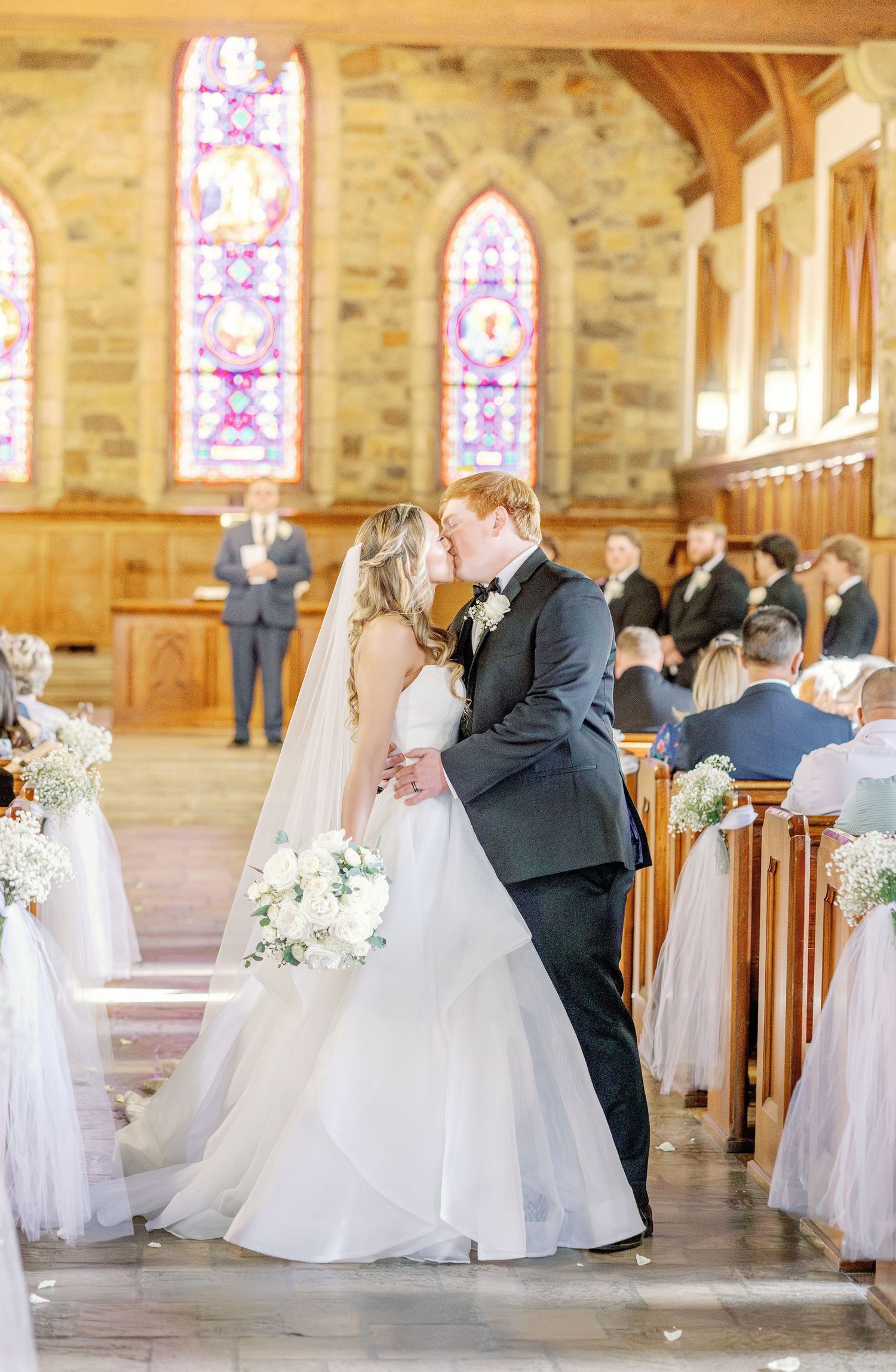 A wedding ceremony captured inside a church with beautiful stained glass windows.