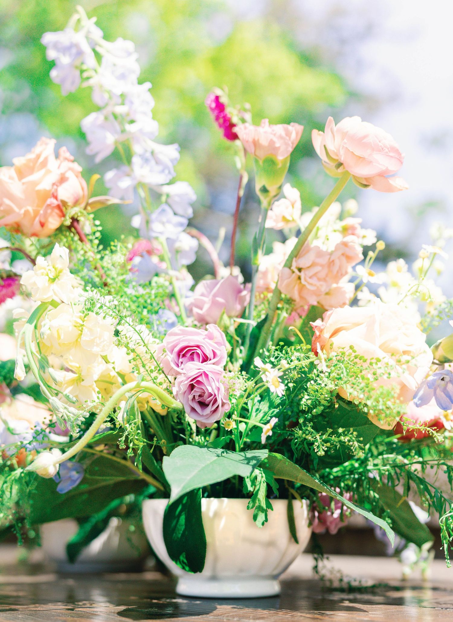 Romantic floral arrangement with peach roses and delicate greenery in a white vase.