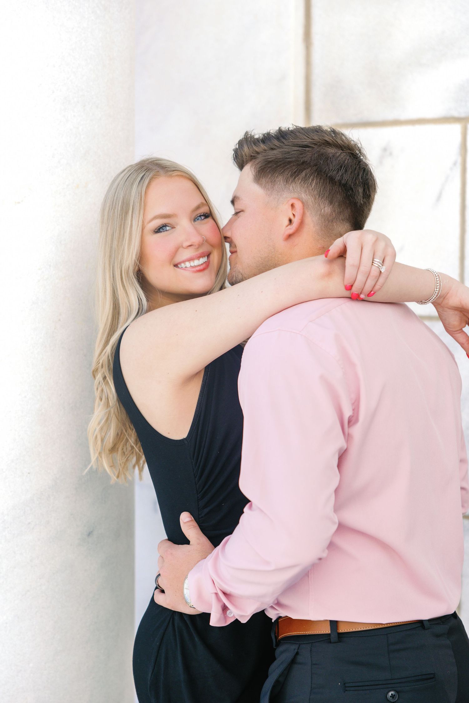 Intimate embrace captured against white architectural backdrop.