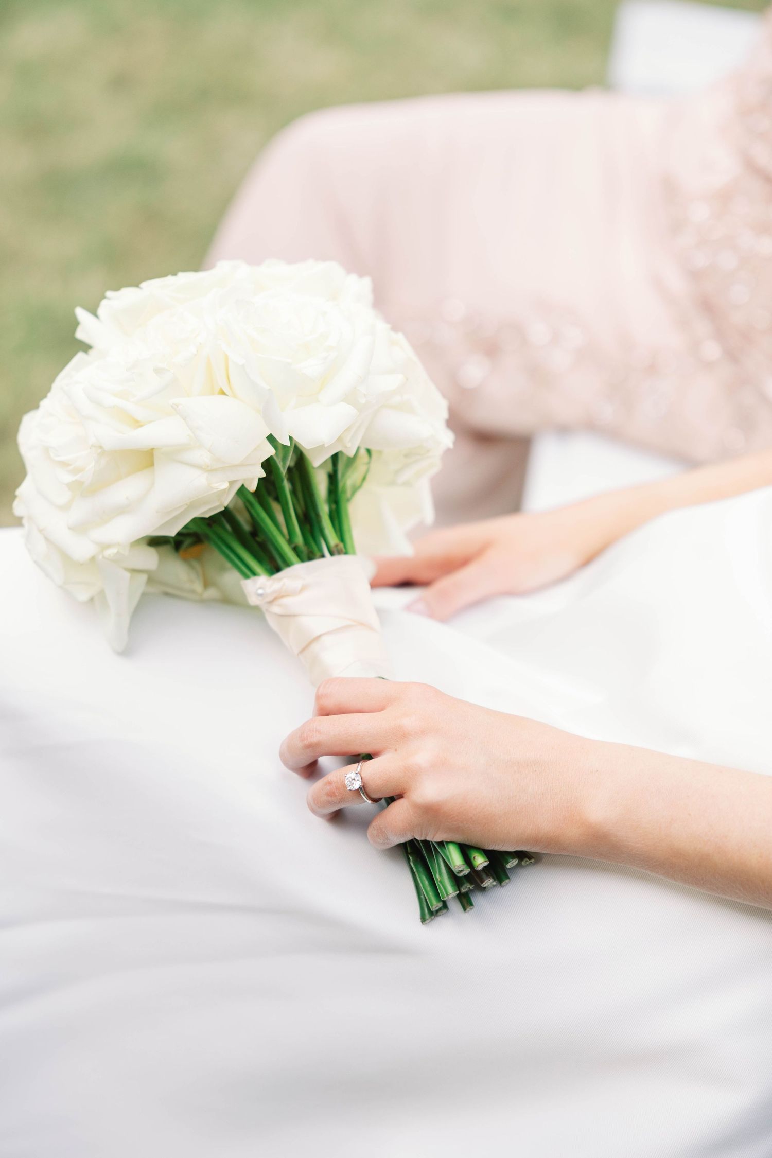 White rose bouquet being wrapped in delicate tissue paper on a light surface.
