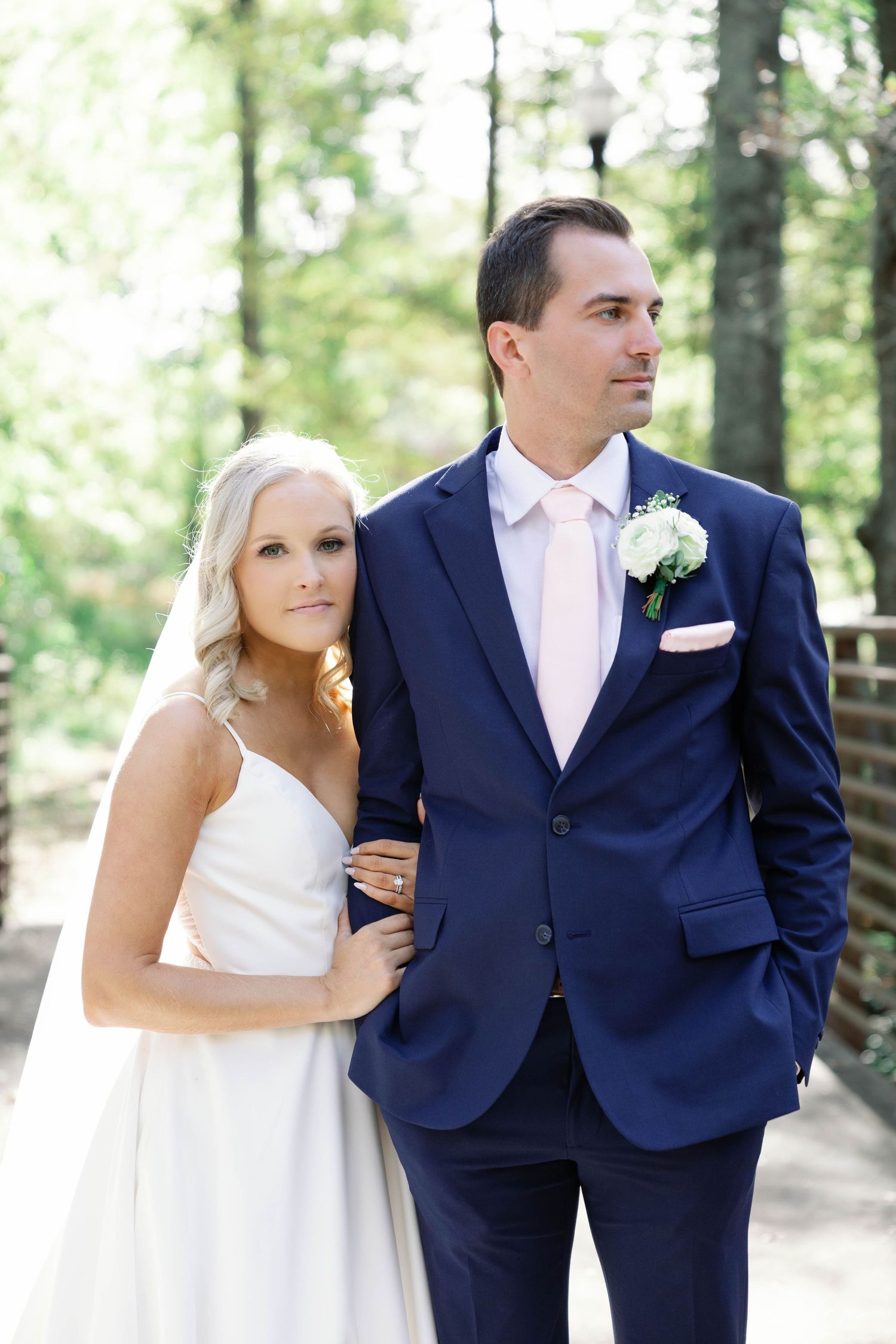 A happy couple in wedding attire share candid moments together in an outdoor wooded setting.