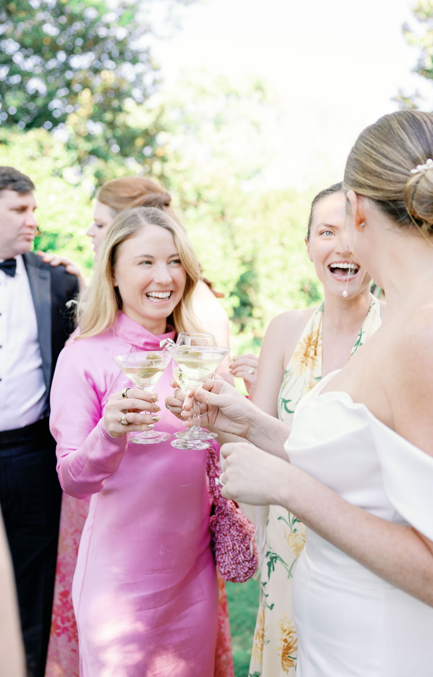 A series of candid photos showing people in pink and white attire laughing and sharing joyful moments at an outdoor event.