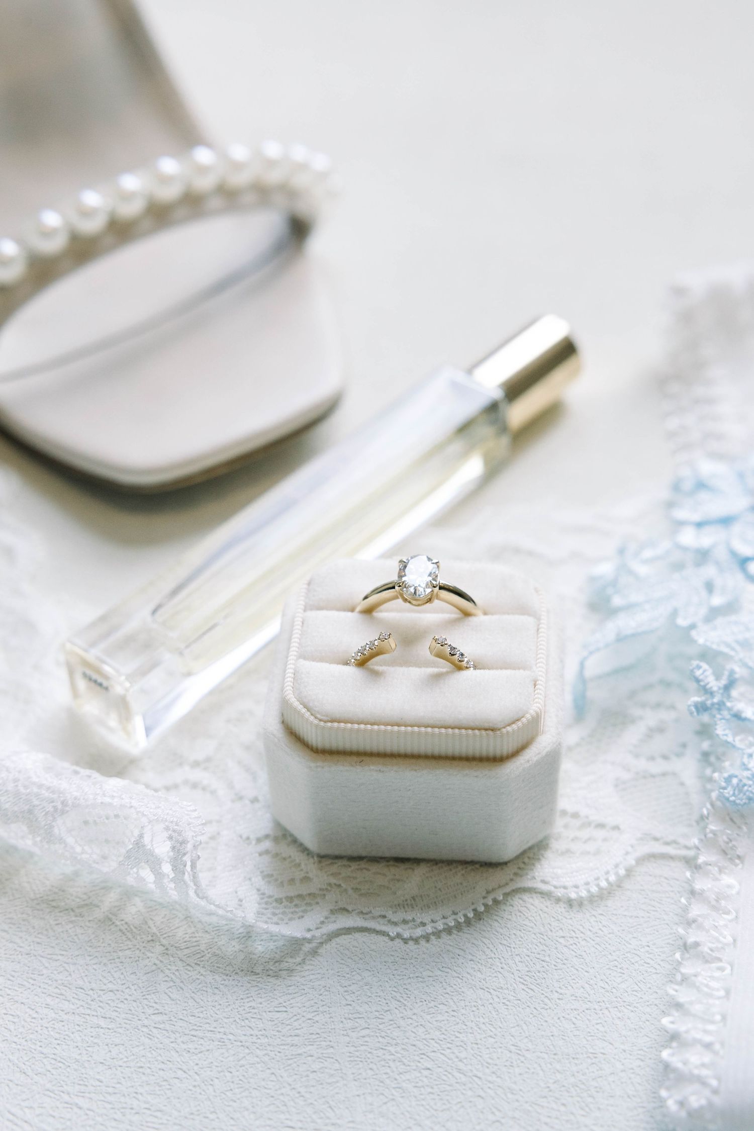 A sequence of white ring boxes displaying an elegant engagement ring set against a delicate pearl necklace.