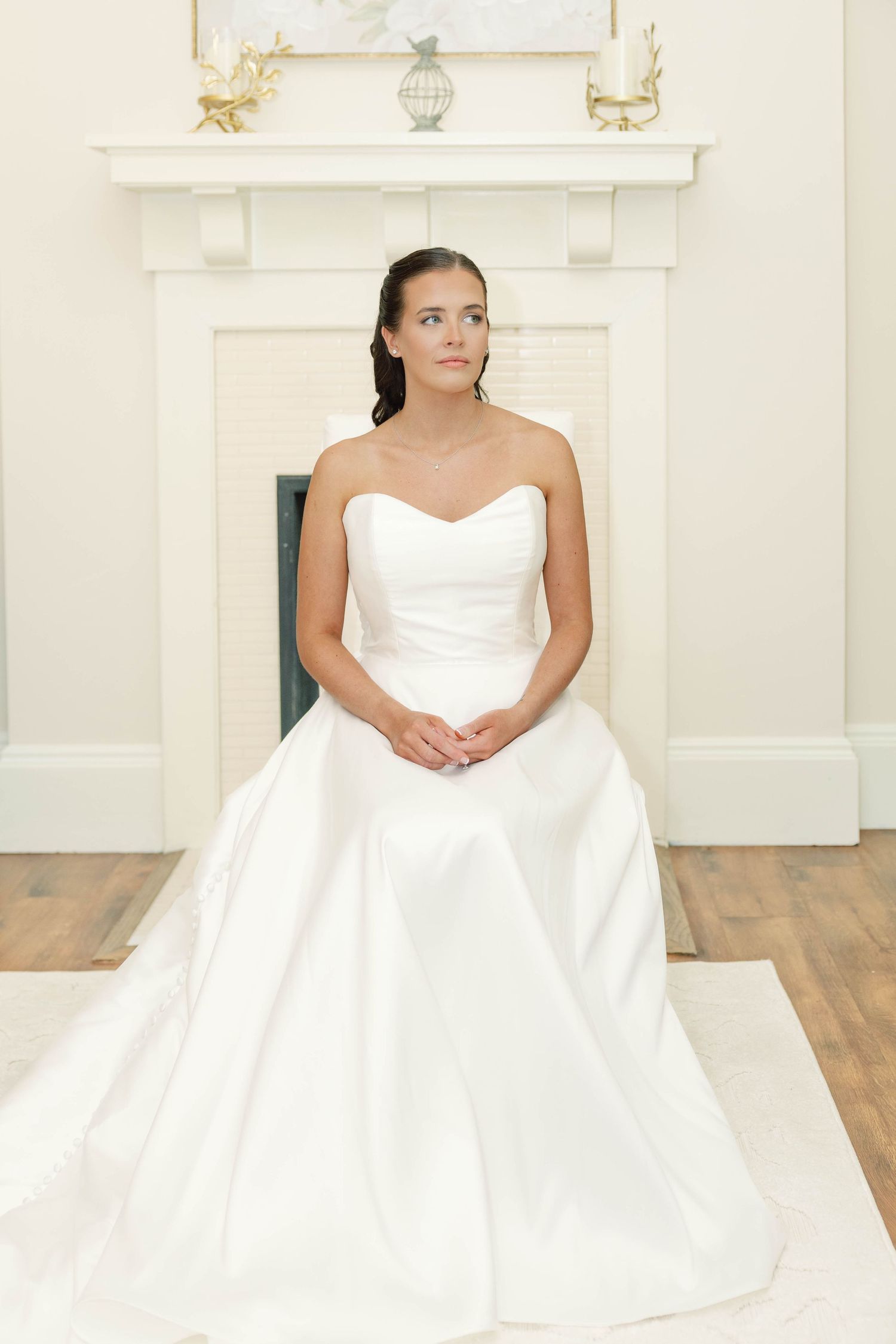 A stunning white wedding gown with a strapless neckline and full skirt is showcased in a bright indoor setting.