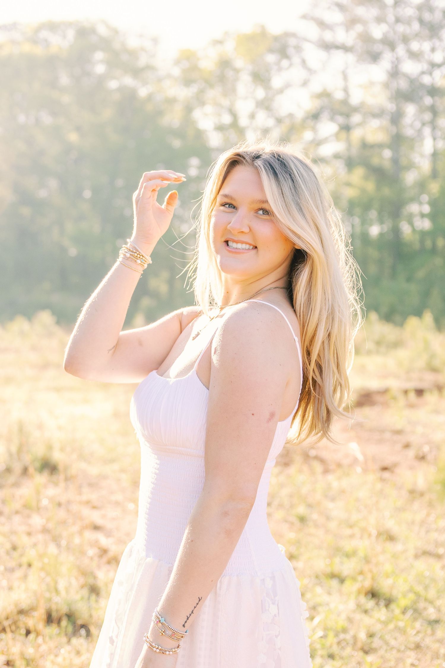 Woman in white dress smiling joyfully in golden hour lighting.