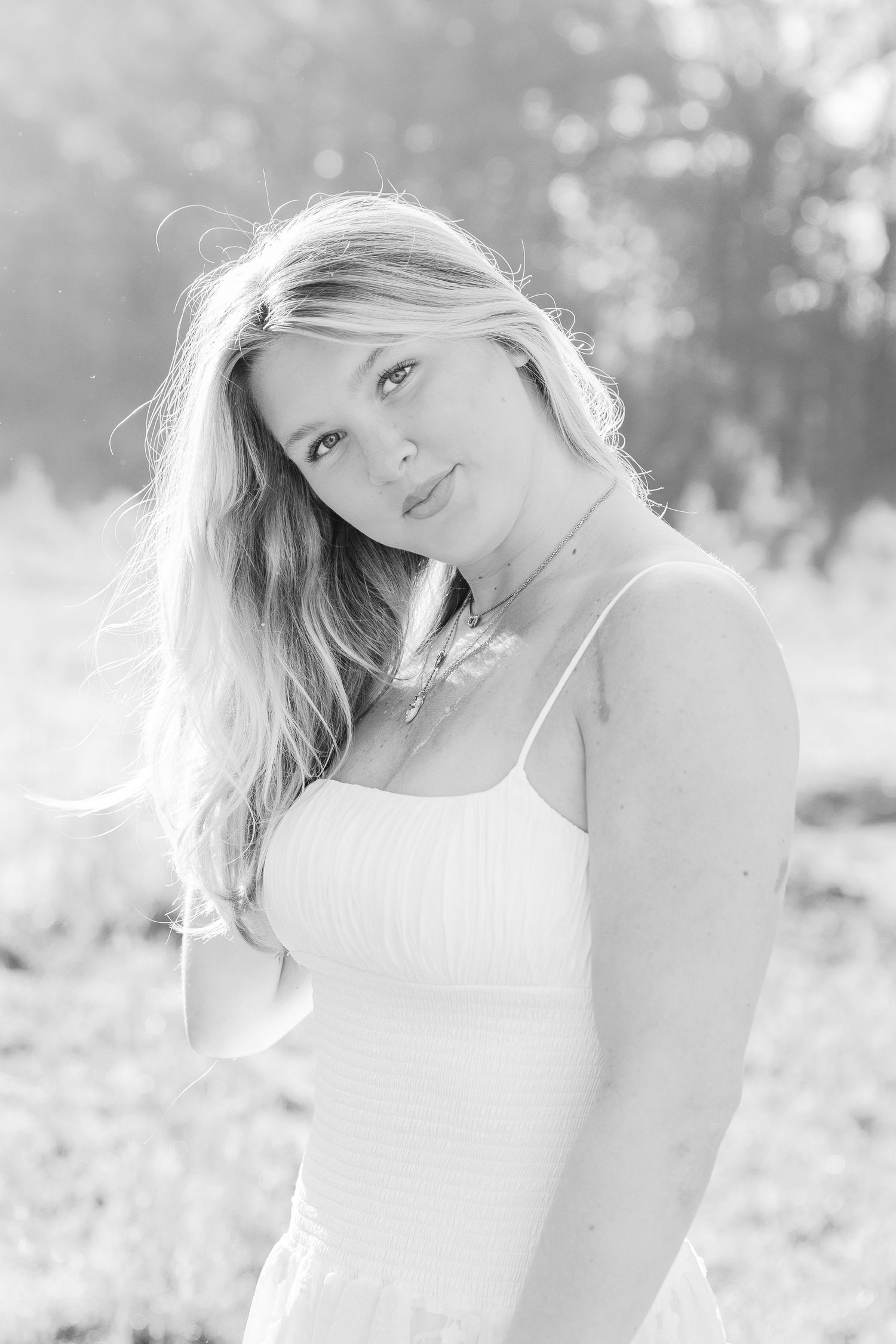 Black and white portrait of a woman with flowing blonde hair in a white dress.