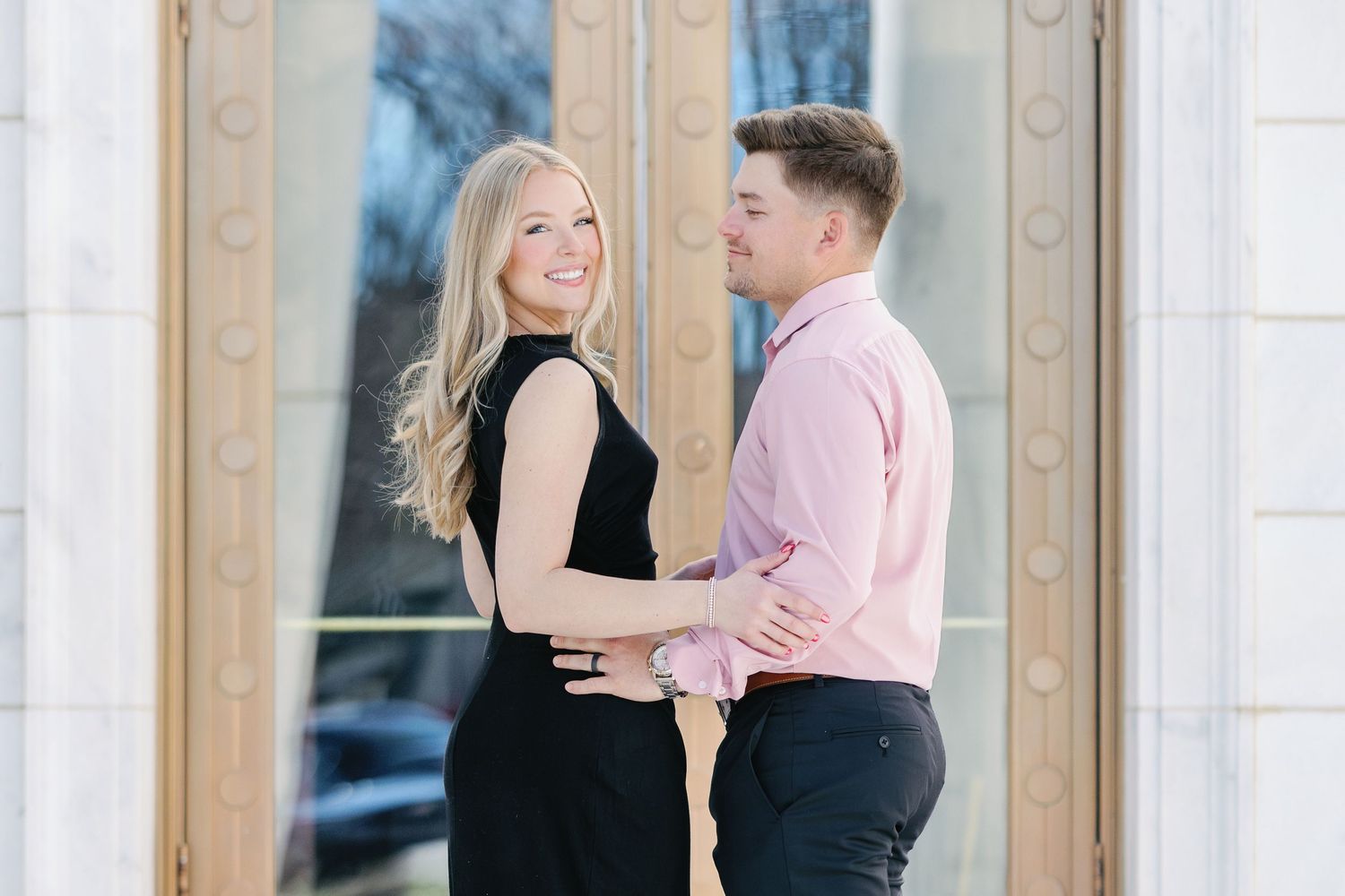 Happy couple in coordinated formal wear share joyful moment at elegant venue entrance.
